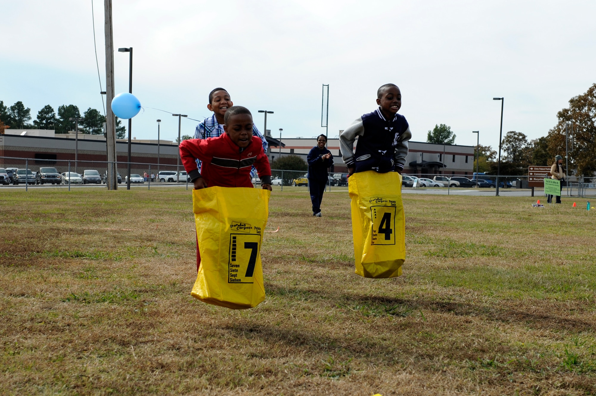 Ramari and Raishawn try to catch up to their brother, Amir, in a sack race, Nov. 8, 2014, at Little Rock Air Force Base, Ark. The sack race was part of the "In It to Win It" course which required participants to complete all activities in order to have the scavenger hunt checklist signed off. (U.S. Air Force photo by Staff Sgt. Jessica Condit)