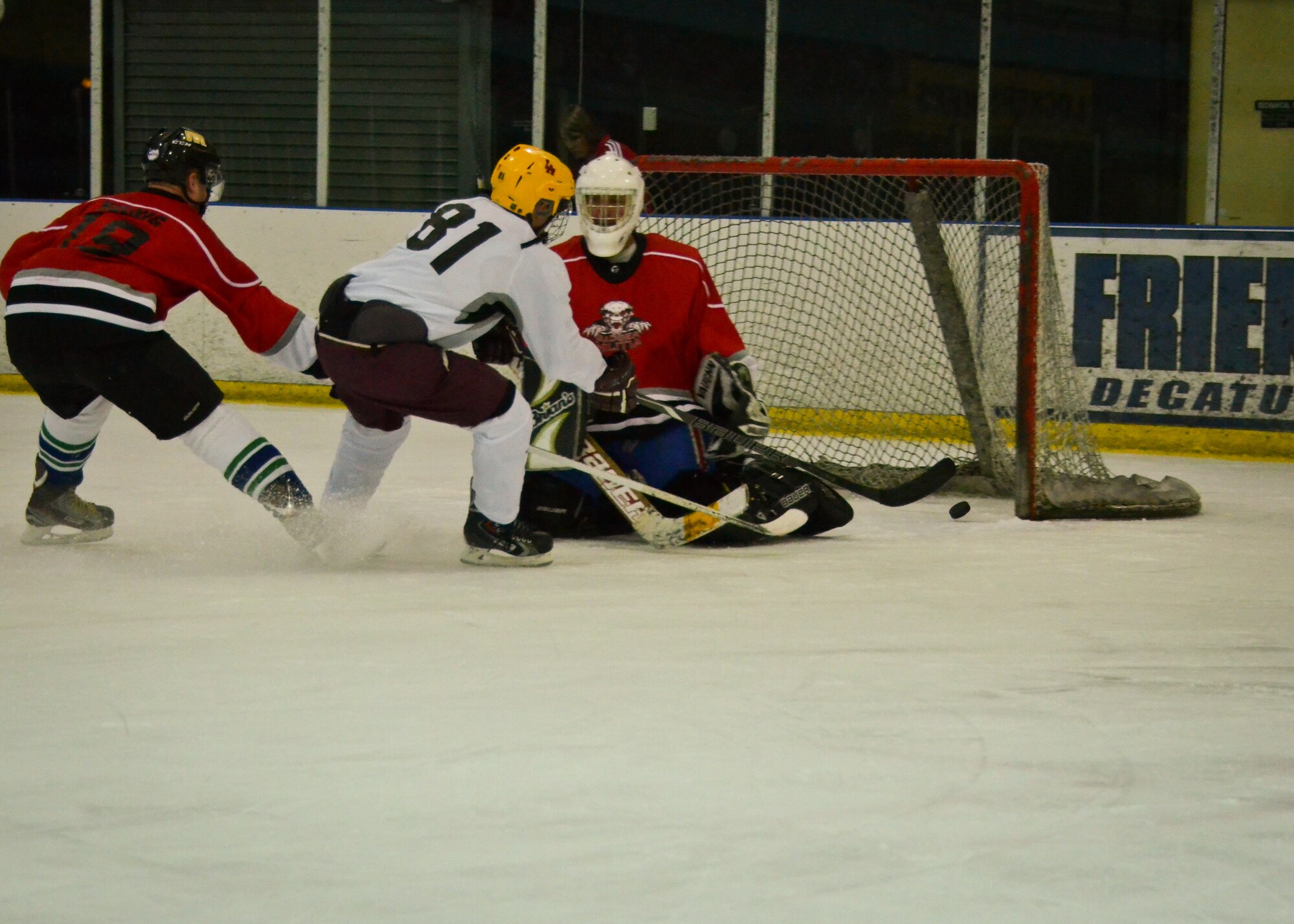 Airman 1st Class Matthew Gaffney, a hockey player with the Brew City Tankers, a team representing the 128th Air Refueling Wing, shoots the puck into the goal of the Badger Militia, a hockey team representing the 115th Fighter Wing and Wisconsin Joint Force Headquarters, at the 2014 Armed Services Hockey Tournament at the Sobe Ice Arena in Las Vegas Nov. 8, 2014.  (U.S. Air National Guard photo by Staff Sgt. Jenna V. Lenski/Released)