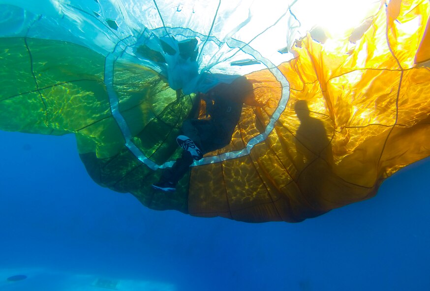 Lt. Col. Ben Aronhime, 56th Training Squadron pilot, navigates his way from one side of an IRVIN-GQ 6000 parachute to another while Staff Sgt. Edwin Portan, 33rd Operations Support Squadron F-35 Lightning II aircrew flight equipment continuation training instructor, assists him from the side of the pool during a water survival class on Eglin Air Force Base, Fla., Oct. 30, 2014. Portan created a floatation device from PVC pipes that prevents the parachute from sinking to the bottom of the pool while students complete their training. The octagon-shaped floatation device creates an effective training environment that provides students with a more closely simulated water landing. (U.S. Air Force photo/Staff Sgt. Marleah Robertson)