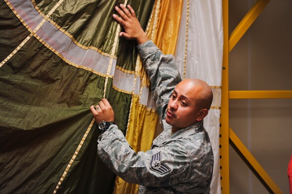 Staff Sgt. Edwin Portan, 33rd Operations Support Squadron F-35 Lightning II aircrew flight equipment continuation training instructor, teaches students about the thicker and heavier material used for the new IRVIN-GQ 6000 parachute during a water survival class on Eglin Air Force Base, Fla., Oct. 30, 2014. Portan created a floatation device from PVC pipes that prevents the parachute from sinking to the bottom of the pool while students complete their training. The octagon-shaped floatation device creates an effective training environment that provides students with a more closely simulated water landing. (U.S. Air Force photo/Staff Sgt. Marleah Robertson)