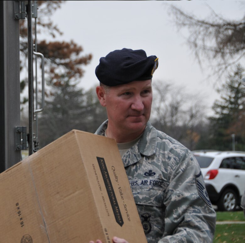 Master Sgt. Joshua Holsinger of the 178th Security Forces Squadron carries a box of donations to the Veterans Resource Center at the Department of Veterans Affairs Medical Center Campus in Dayton Ohio, Nov. 11 as part of an event to honor veterans. The Veterans Resource Center shelter is run by the Volunteers of America of Greater Ohio organization, which provides transitional housing and employment services for homeless veterans. (Ohio Air National Guard photo by Capt. Michael Gibson/Released)