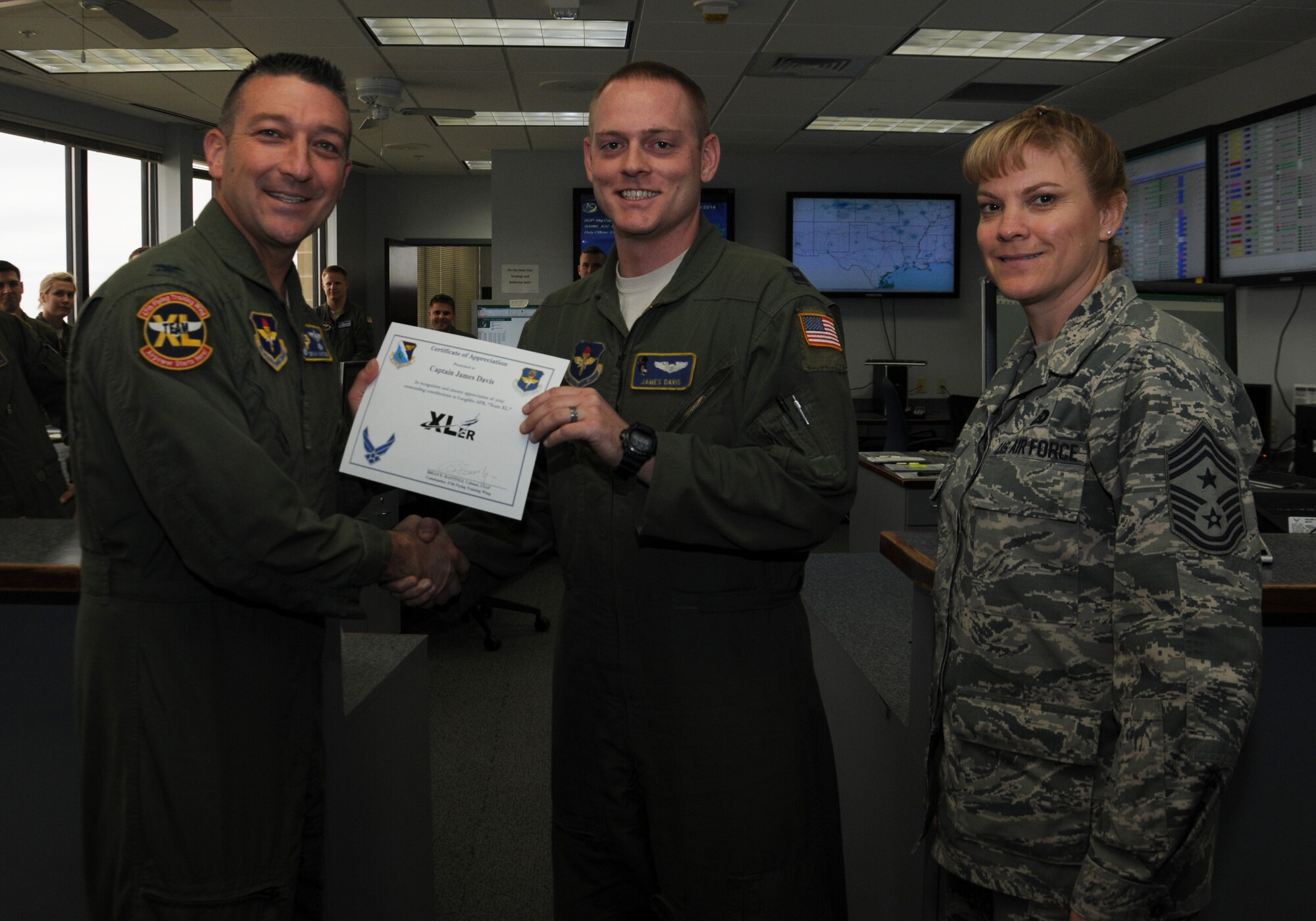 Capt. James Davis, center, 86 Flying Training Squadron programmer, poses with Col. Brian Hastings, left, 47th Flying Training Wing commander, and Chief Master Sgt. Teresa Clapper, right, 47th FTW command chief, after being presented the XLer of the week award here Nov. 12, 2014. The XLer is a weekly award chosen by wing leadership and is presented to those who consistently make outstanding contributions to their unit and Laughlin. (U.S. Air Force photo by Airman 1st Class Ariel D. Delgado)(Released)