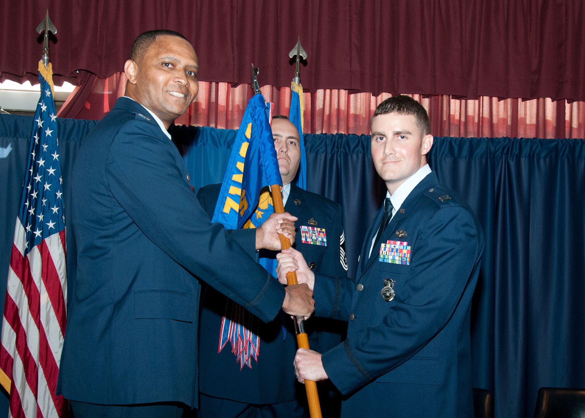 Col. Christopher Daniels (left), the 71st Mission Support Group commander, passes the 71st Security Forces Squadron guidon to Capt. Christopher Jackson during a change-of-command ceremony at the Vance Collocated Club Nov. 10. Jackson joined Team Vance after a tour as the deputy chief, Contingency and Future Operations, United States Air Forces Europe, Ramstein Air Base, Germany. (U.S. Air Force photo/Terry Wasson)