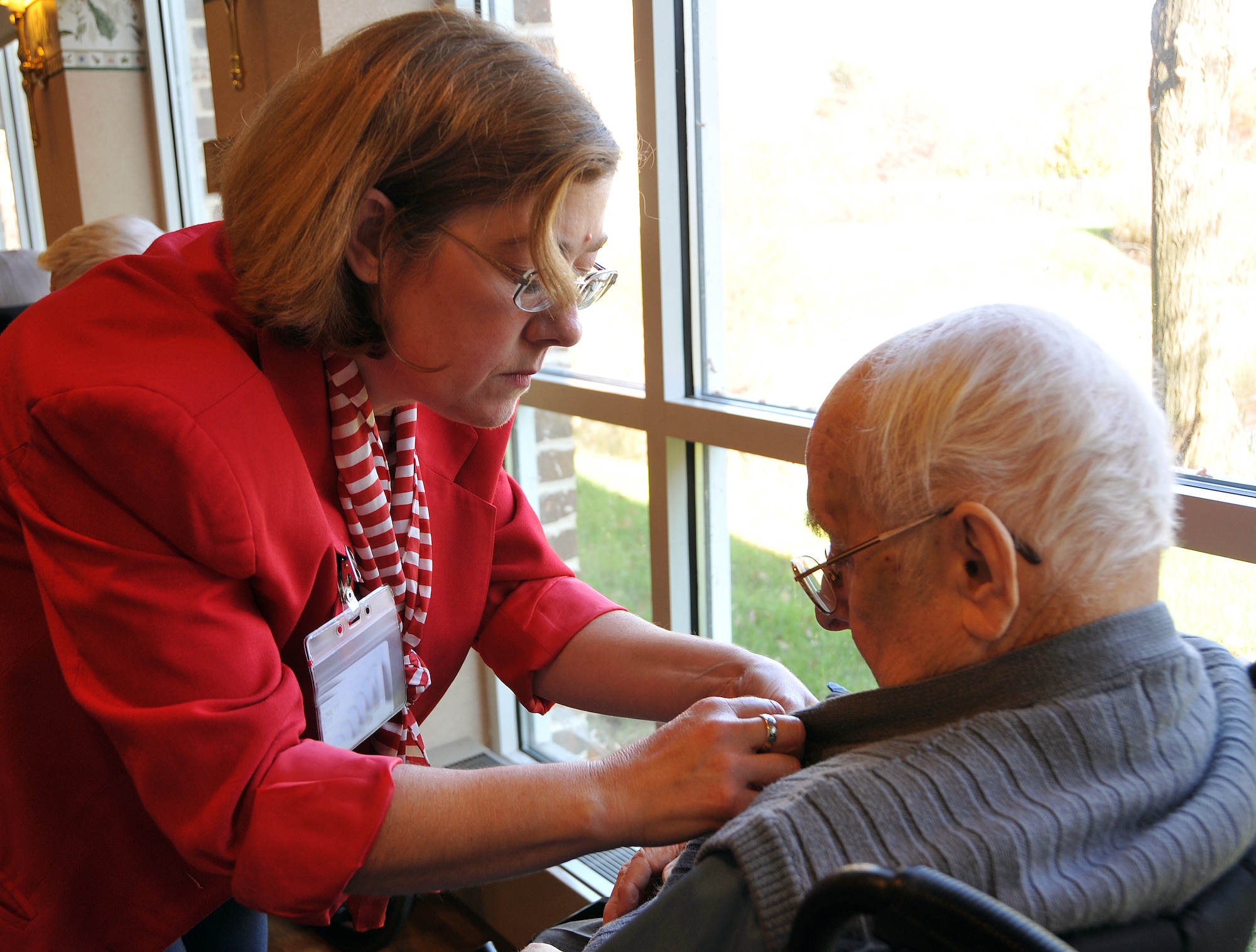 Lisa Hackett, programming coordinator for Oak Ridge Village retirement community’s assisted-living facility in Parkville, Md., presents an honorary pin to World War Two-veteran Joseph Radecki during a Veterans Day ceremony Nov. 11. Radecki served as a U.S. Navy flight engineer from 1940-44. (U.S. Army photo by Staff Sgt. Shawn Morris/Released)