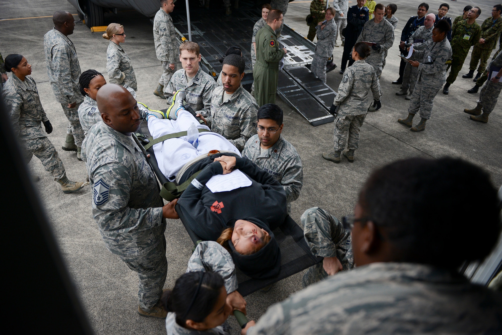Airmen assigned to the 374th Medical Group move a patient to a bus for transportation during a medical evacuation training scenario for Exercise Keen Sword 2015 at Yokota Air Base, Japan, Nov. 12, 2014. The patients were put on different buses depending on their health status and transported to one of three facilities to receive necessary medical care. (U.S. Air Force photo by Staff Sgt. Cody H. Ramirez/Released)