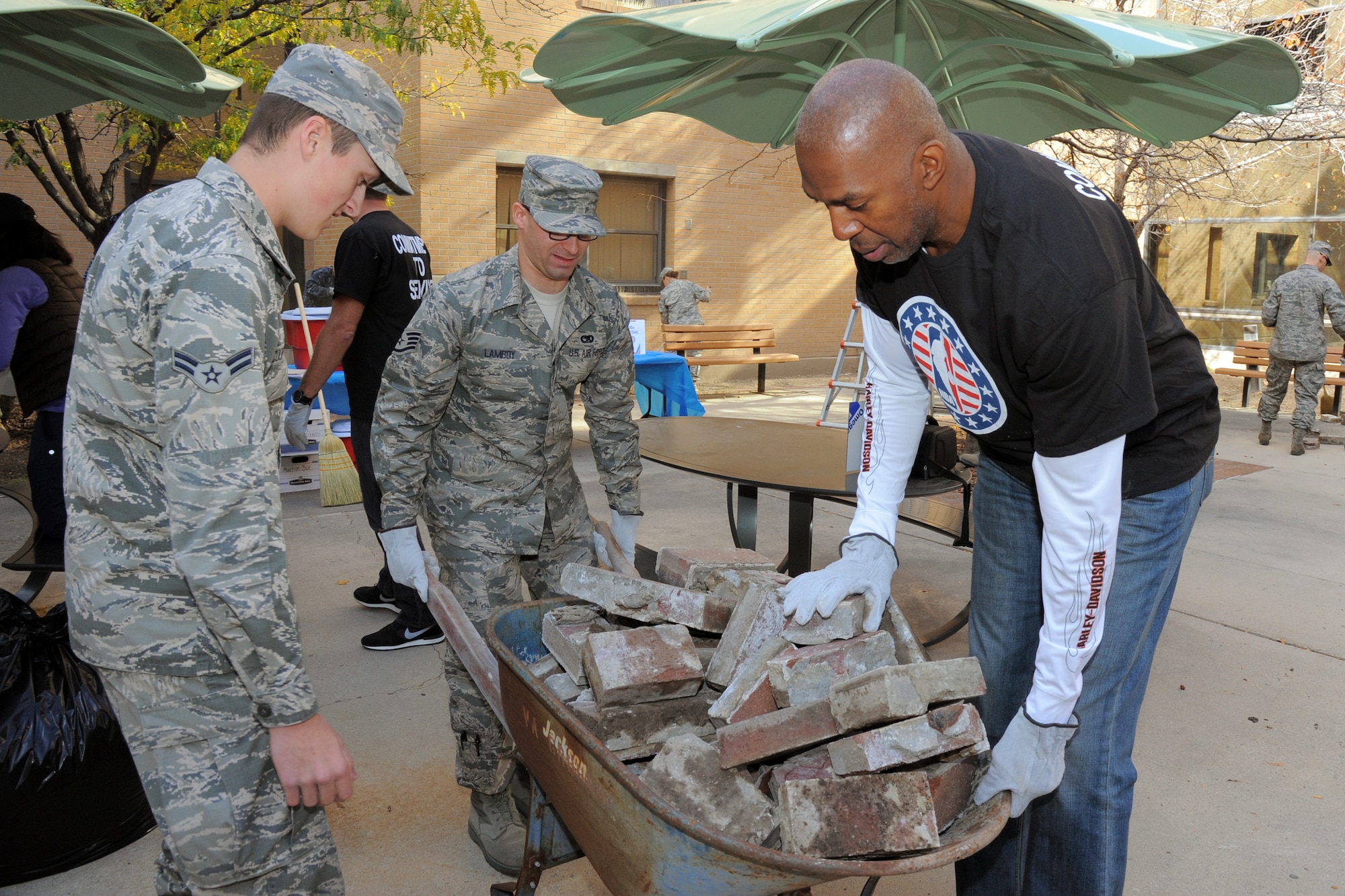 Airman 1st Class Shane Coopmans (left), Staff Sgt. Albert Lamboy and Thurl Bailey, a former NBA player with the Utah Jazz, dispose of old bricks during a community service project Nov. 6, 2014, at the George E. Whalen Veterans Affairs Medical Center in Salt Lake City, Utah. Coopmans is with the 75th Operations Support Squadron and Lamboy serves with the 75th Logistics Readiness Squadron. (Air Force photo/Todd Cromar)