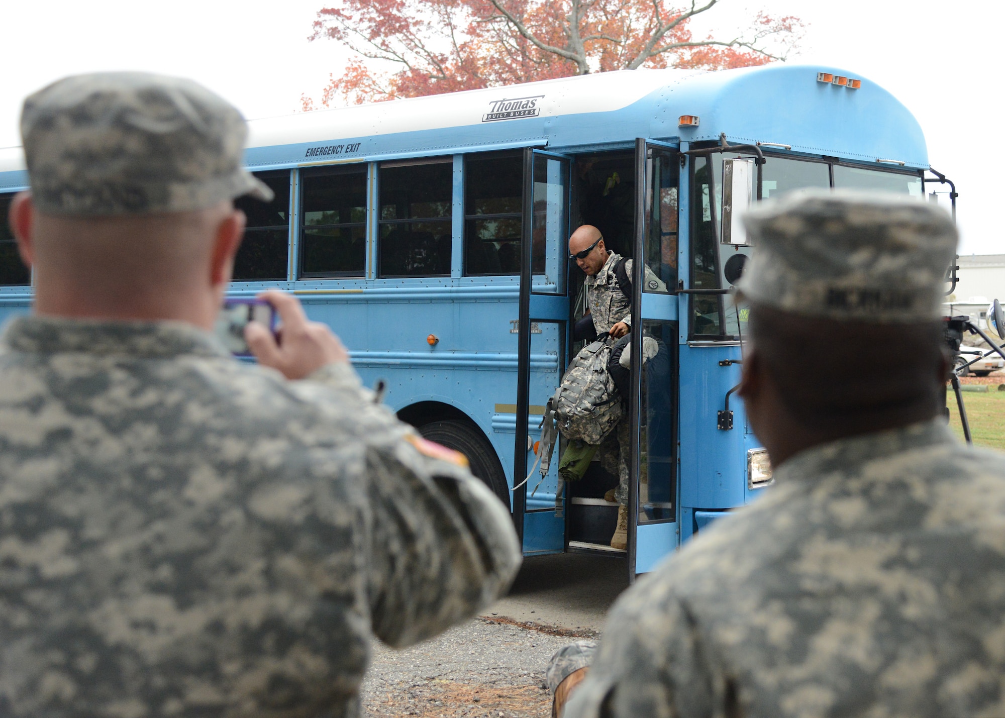 Soldiers look on as service members disembark a bus upon arrival at Langley Transit Center Nov. 13, 2014, at Langley Air Force Base, Va. Service members from multiple branches of the armed forces will undergo a 21-day controlled monitoring period at the transit center after returning from fighting the spread of Ebola in West Africa in support of Operation United Assistance. (U.S. Air Force photo/Staff Sgt. Jason J. Brown)