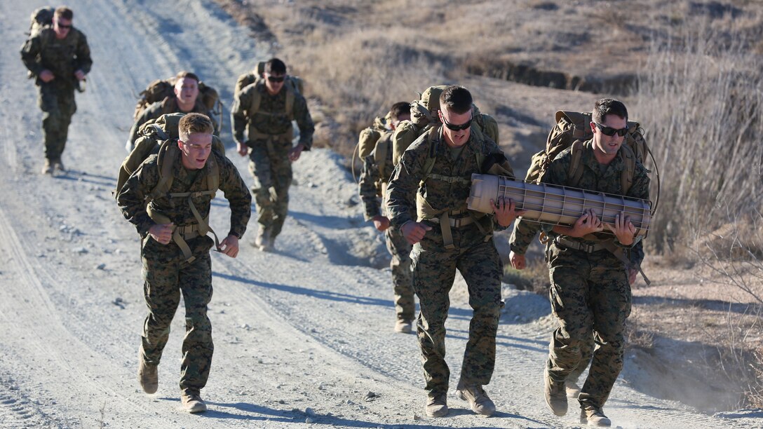 Marines with Force Company, 1st Reconnaissance Battalion, 1st Marine Division hike with 50-pound packs and carry a 60-pound container full of sand during a physical training exercise aboard Marine Corps Base Camp Pendleton, Calif., Nov. 7, 2014. The physical training exercise also incorporated activities to improve proficiency in marksmanship and memorization.