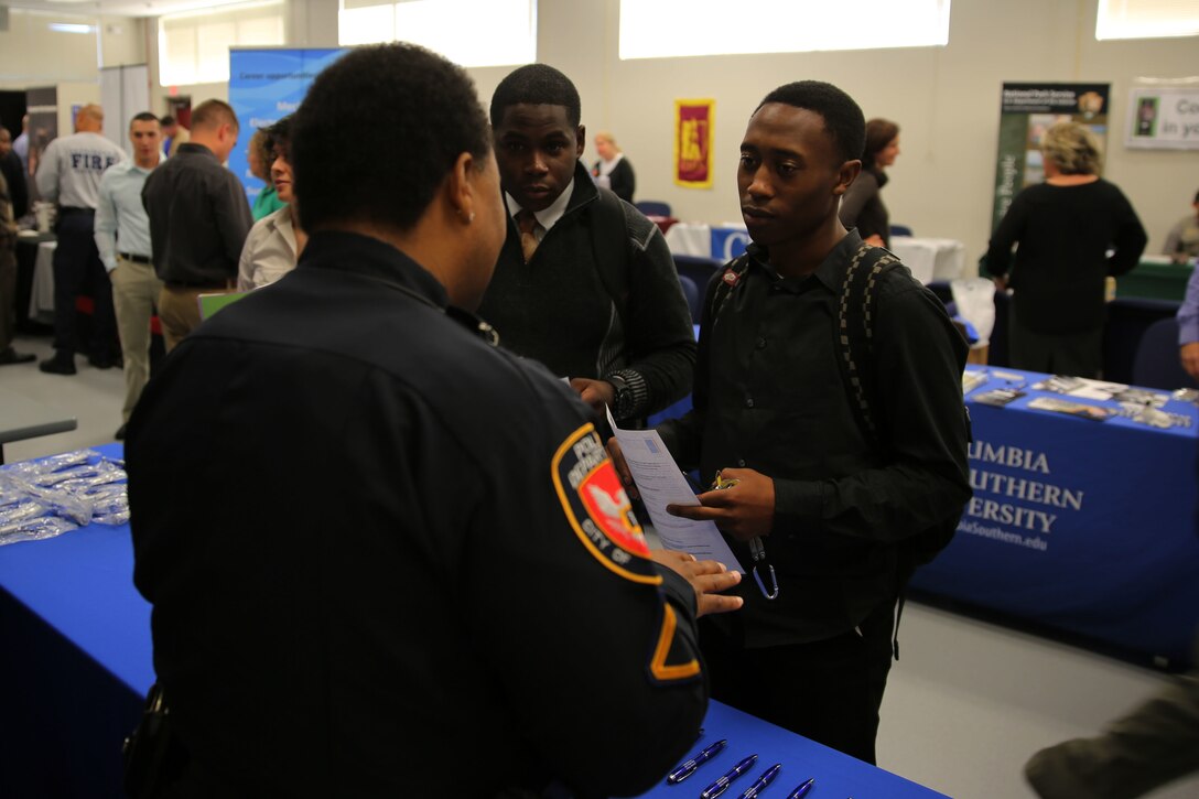 Lance Cpl. Sean Nesbitt, left, and Lance Cpl. DuWaye Jones speak with a representative from the City of Durham Police Department during the career education fair at Marine Corps Air Station Cherry Point, N.C., Nov. 7, 2014. Nesbitt is an aircraft electrical systems technician with Marine Attack Squadron 542 and Jones is a fixed-wing aircraft mechanic with Marine Attack Squadron 223.