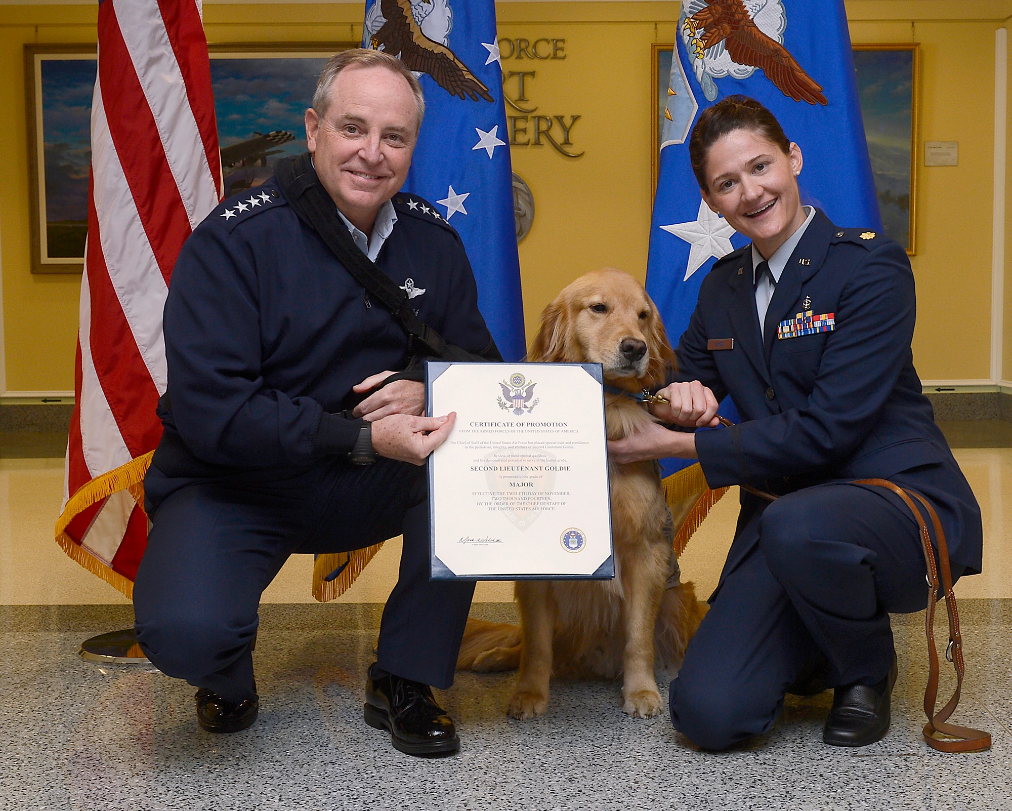 Air Force Chief of Staff Gen. Mark A. Welsh III (left) promotes 2nd Lt. Goldie, a therapy dog from Walter Reed National Military Medical Center, to the rank of major, with Maj. Regina Owens, a psychiatric nurse, Nov. 12, 2014, in the Pentagon. The ceremony highlights one of the secretary of the Air Force priorities, "Taking Care of People." Goldie, along with a team of therapy dogs, provides comfort to the hospital's patients and family members.  (U.S. Air Force photo/Scott M. Ash)  