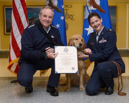 Air Force Chief of Staff Gen. Mark A. Welsh III (left) promotes 2nd Lt. Goldie, a therapy dog from Walter Reed National Military Medical Center, to the rank of major, with Maj. Regina Owens, a psychiatric nurse, Nov. 12, 2014, in the Pentagon. The ceremony highlights one of the secretary of the Air Force priorities, "Taking Care of People." Goldie, along with a team of therapy dogs, provides comfort to the hospital's patients and family members.  (U.S. Air Force photo/Scott M. Ash)  