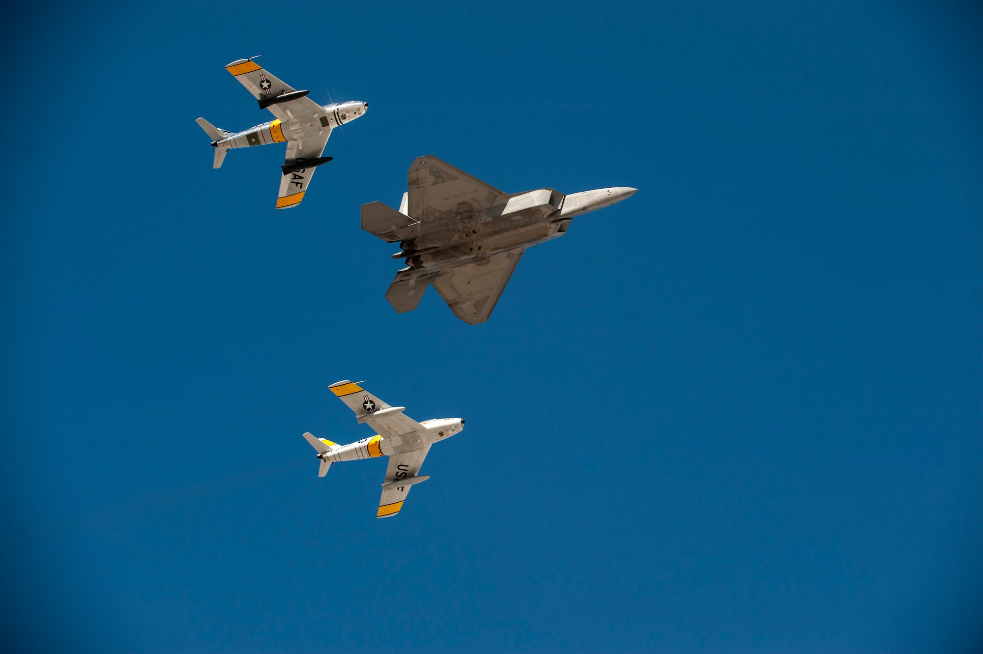 An F-22 Raptor from the 53rd Test and Evaluation Group and two F-86 Sabres fly overhead during the heritage flight at the open house at Nellis Air Force Base, Nev., Nov. 7, 2014. The heritage flight is done to show the U.S. Air Force’s past and present capabilities. (U.S. Air Force photo by Airman 1st Class Thomas Spangler)