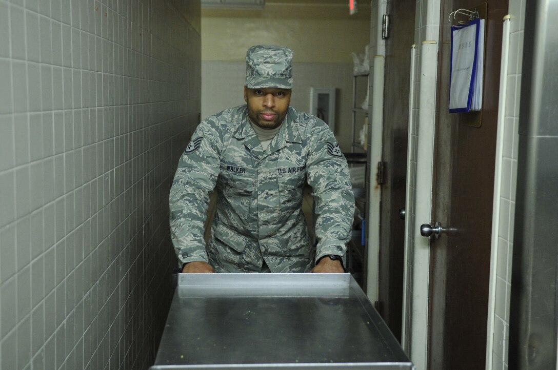 Staff Sgt. Marcus Walker, 325th Force Support Squadron dining facility shift leader, pushes a metallic food tray at the Berg-Lilies dining facility Nov. 14 at Tyndall. Personnel at the dining facility are responsible for providing sustenance to service members and civilians on base. (U.S. Air Force photo by Airman 1st Class Ty-Rico Lea)