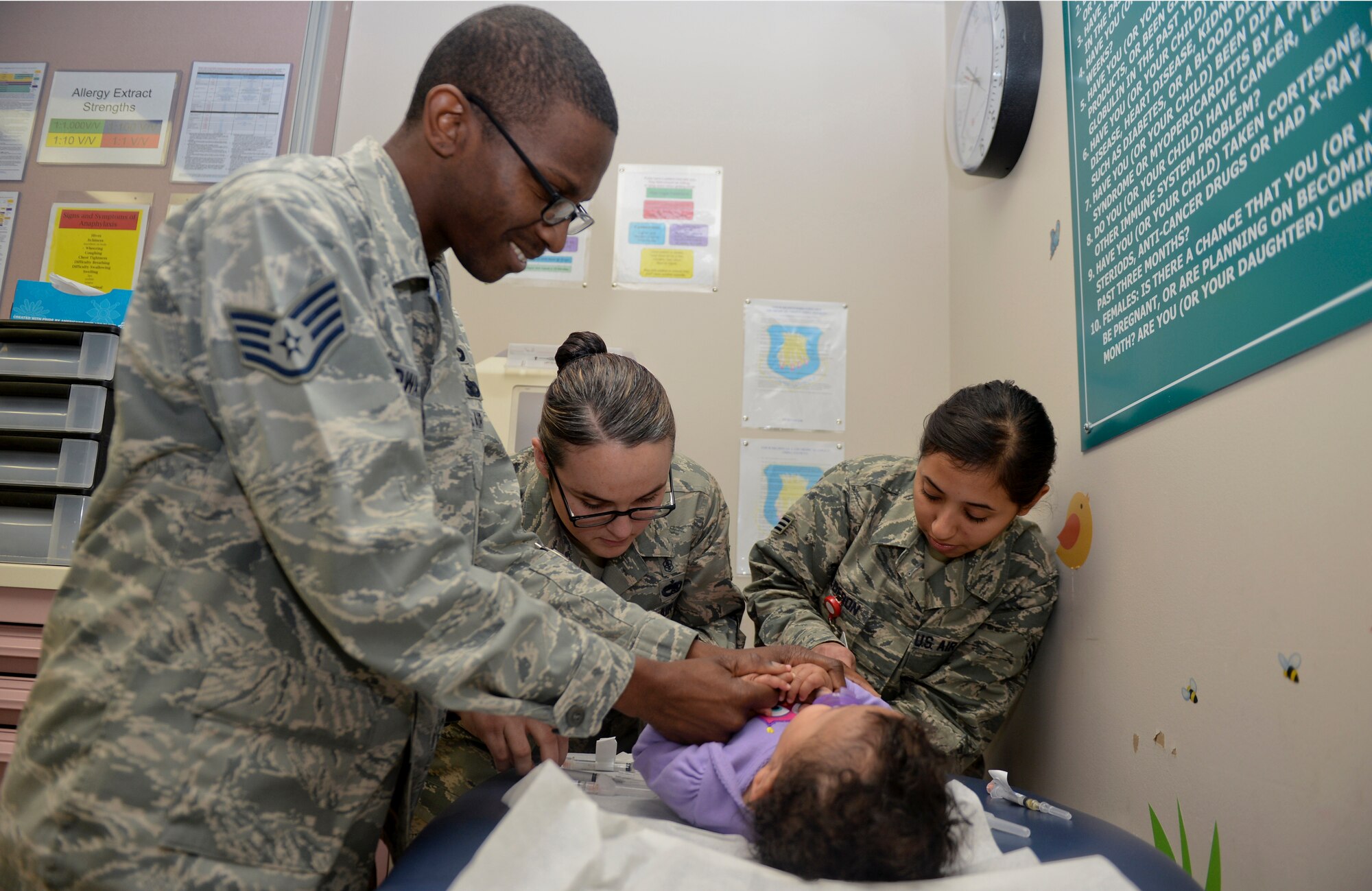 Tech. Sgt. Megan Hay, 22nd Medical Operations Squadron, allergy and immunizations NCO in charge and Senior Airman Jesenia Calderon, 22nd MDOS medical technician, give a flu shot to Avery Edwards, 1, while her father Staff Sgt. Byron Edwards, 22nd Air Refueling Wing chapel program support, holds her hand to comfort her, Nov. 14, at McConnell Air Force Base, Kan. With flu season around the corner, members of Team McConnell are encouraged to stop by the immunizations office to receive their annual flu vaccinations. (U.S. Air Force photo/Airman 1st Class Colby L. Hardin)