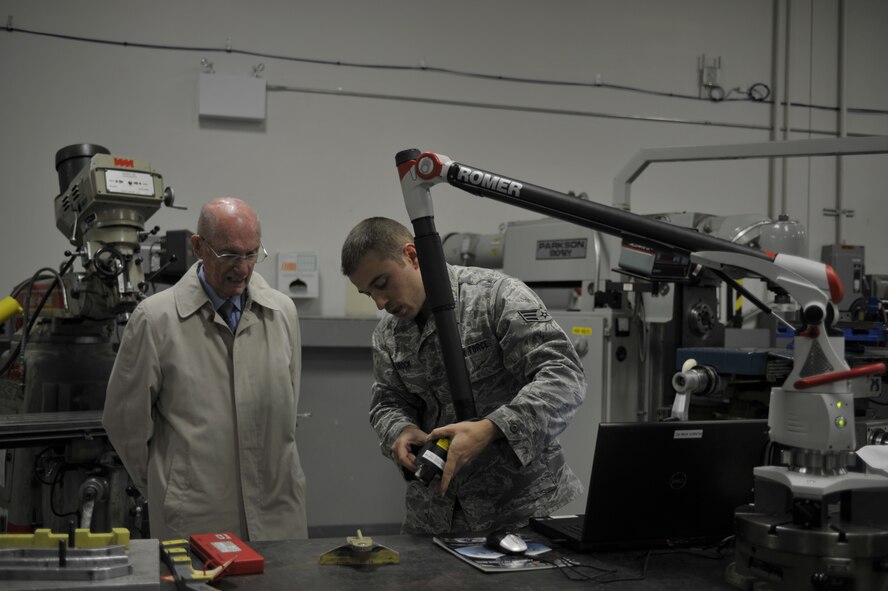 Senior Airman Jerry Brock, 92nd Maintenance Group aircraft metals technology specialist, demonstrates the use of a ROMER Absolute Arm to retired Chief Master Sgt. of the Air Force James McCoy Nov. 12, 2014, on Fairchild Air Force Base, Wash. Brock explains that the ROMER Absolute Arm helps them take electronic measurements of damaged pieces in half as much time as doing it manually. (U.S. Air Force photo/Airman 1st Class Taylor Bourgeous)