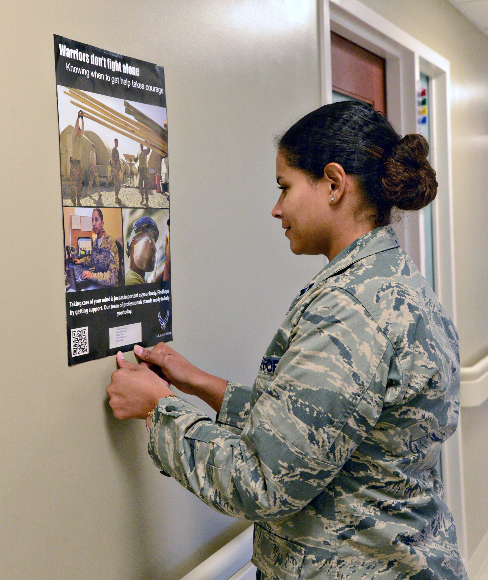 Capt. Mayrin Munguia, officer-in-charge of Mental Health, hangs posters in the hallways of the 72nd Medical Group for Airman to be aware of various services available and to get support if needed and to also offer support to other Airmen in need. (Air Force photo by Kelly White)