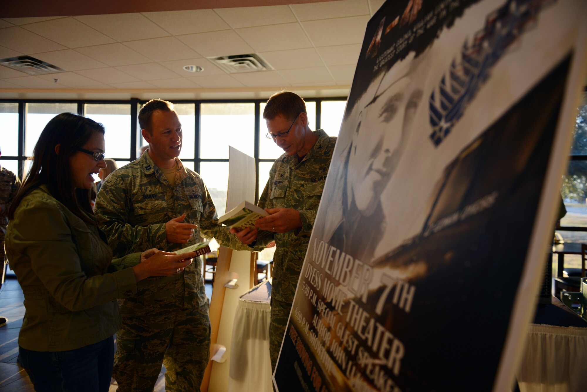 U.S. Air Force Col. Robert Bogart, right, 7th Medical Group commander, his wife, Kim, and Capt. Jacob Bailey view books before the showing of the movie “4-4-43” Nov. 7, 2014, at Dyess Air Force Base, Texas. The documentary tells the story of Lt. Col. William Dyess’ early life, his narrative of the war crimes committed against prisoners of war by the Japanese during World War II, and his life up until his death at the age of 27. (U.S. Air Force photo by Airman 1st Class Kedesha Pennant/Released)