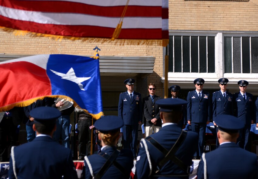 Leaders from Dyess Air Force Base and the Abilene community stand in silence as Taps is played Nov. 8, 2014, in Abilene, Texas. Airmen from Dyess joined community military support agencies, JROTC units and high school marching bands in the annual Taylor County Veterans Day Parade. The Dyess honor guard led the parade after stopping at the viewing stand to present the U.S. and state flags. (U.S. Air Force photo by Senior Airman Peter Thompson/Released)