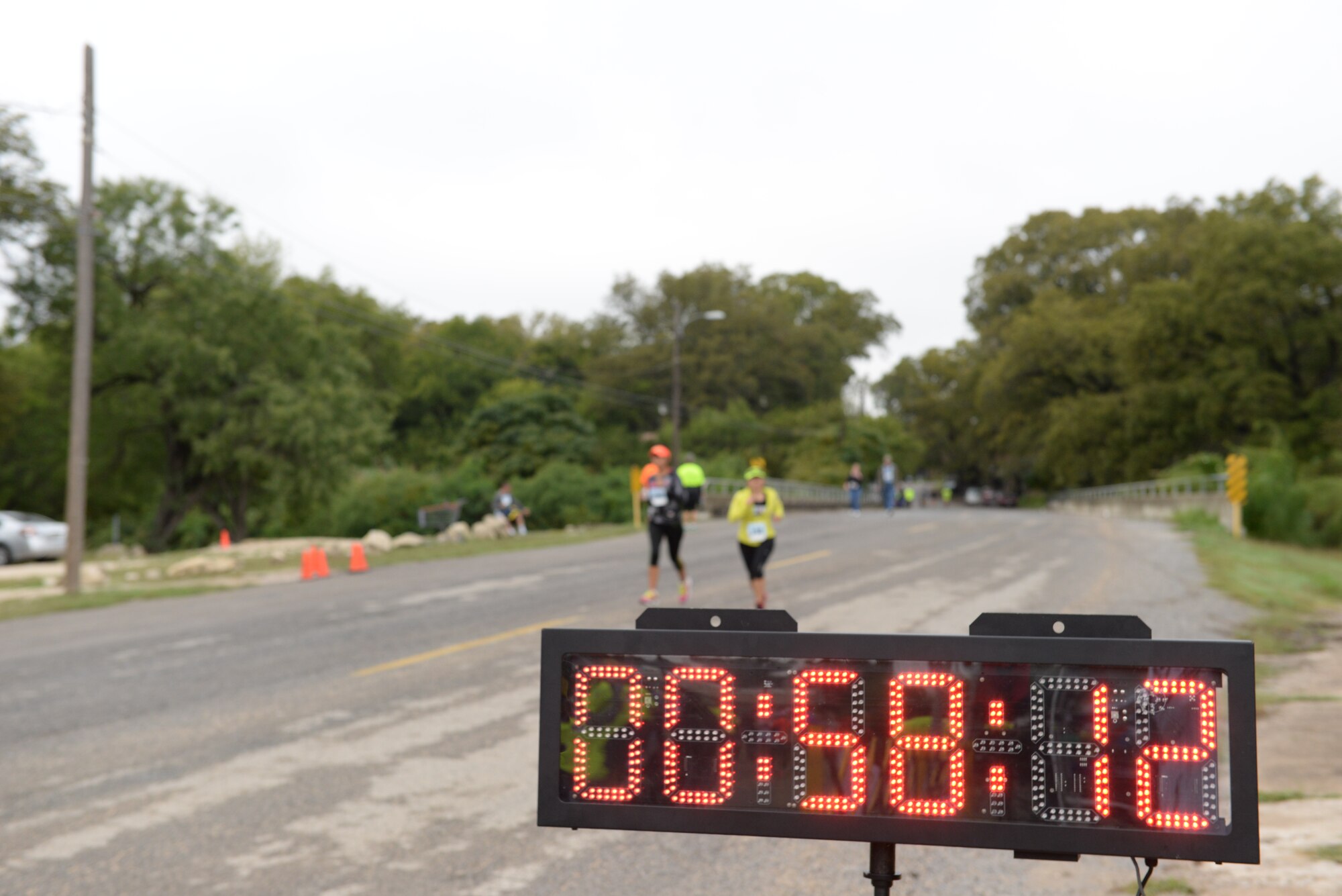 Runner’s pass the finish-line as a clock keeps their time at the 4th annual Running with the Bulls 5K and 10K in Del Rio, Texas, Nov. 8, 2014. Val Verde Loaves and Fishes’ Running with the Bulls race is their only fundraising event for the year to supplement donations and on average raises around $50,000. (U.S. Air Force photo by Airman 1st Class Jimmie D. Pike)(Released)