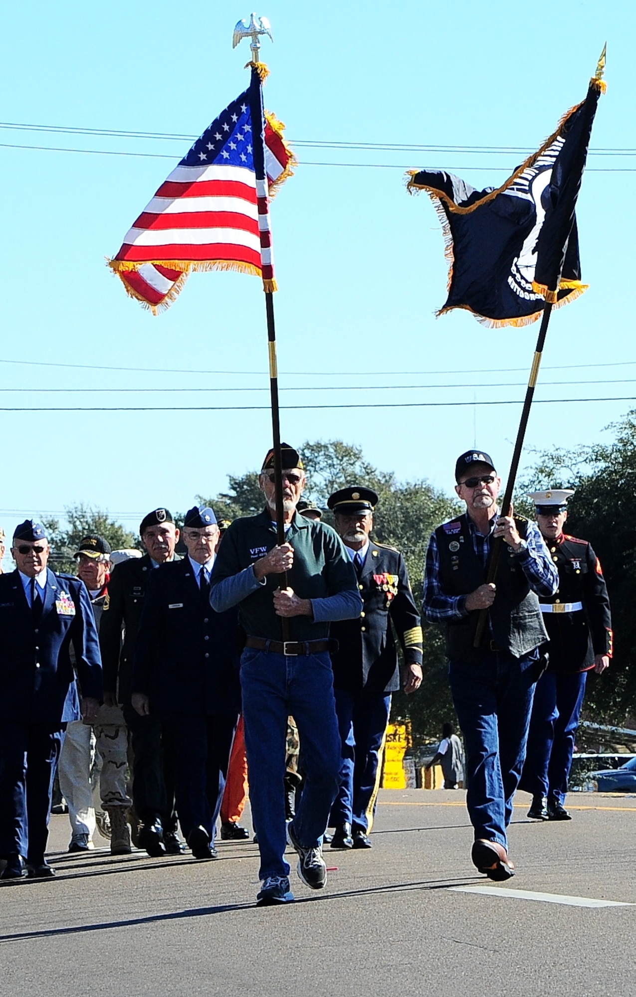 A formation of retired veterans marches down the street during the Veterans Day parade Nov. 8 through Main Street in Columbus, Mississippi. Leading the formation were the American flag and a Prisoner of War/Missing in Action flag. (U.S. Air Force photo/Airman John Day) 