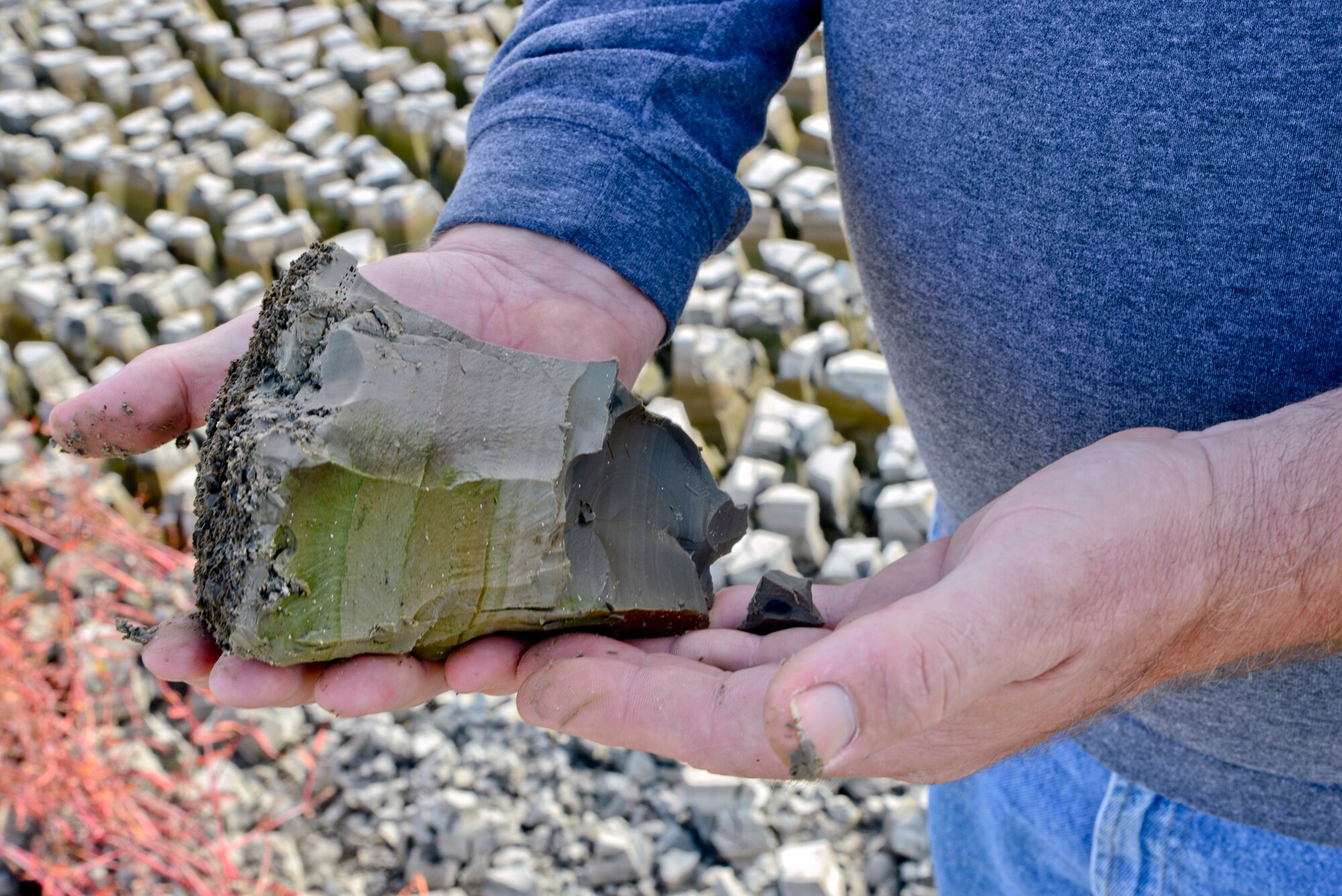 Roger Kasper, senior water treatment plant operator, holds a handful of sludge from the sludge drying bed. Sludge is extracted from the water during the sedimentation phase, and is then transported to sludge drying beds for one to three months before disposal. (U.S. Air Force photo/Senior Airman Madelyn Brown).

