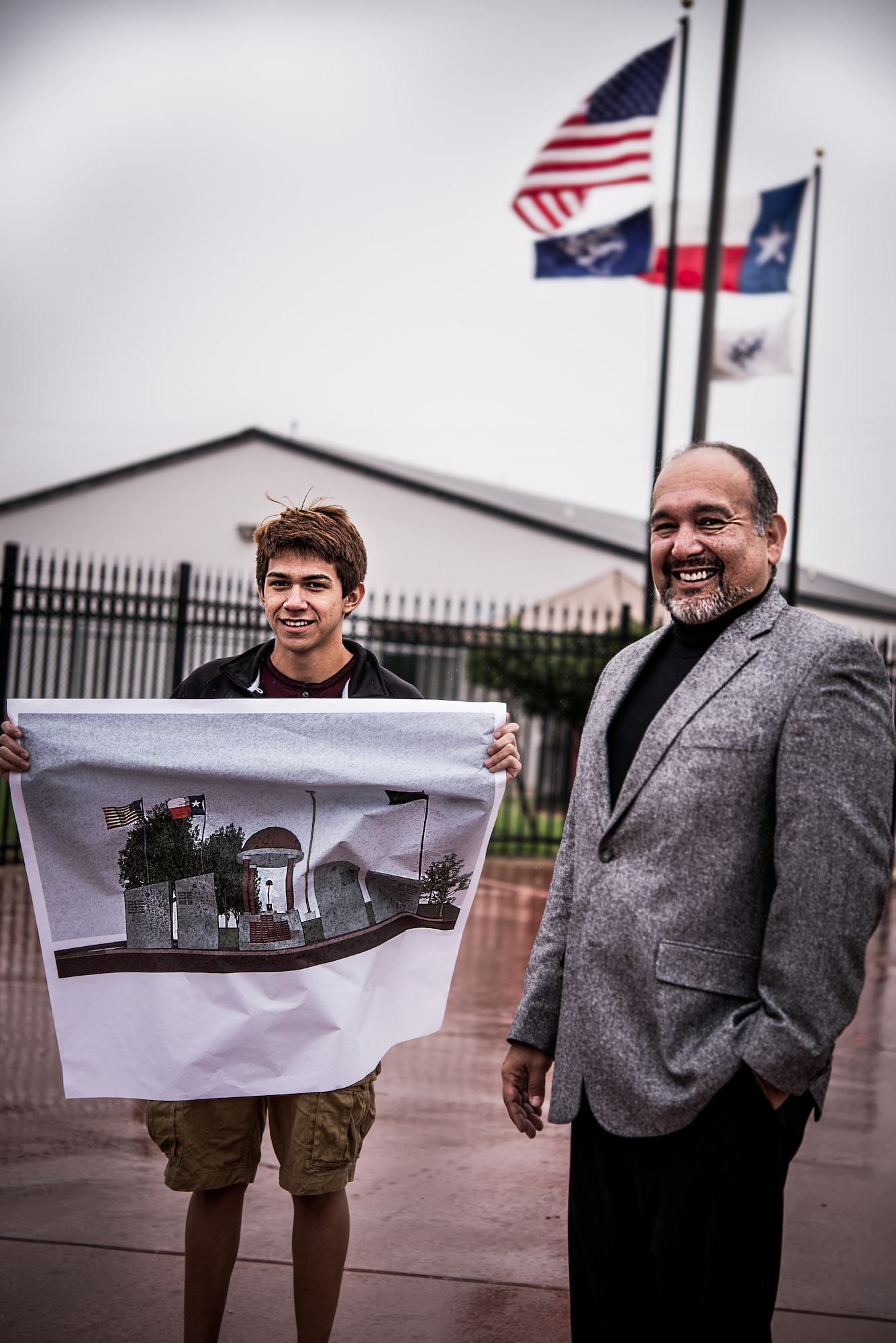 Julio Zamora, a senior at South San Antonio High School, and architect Jorge Flores stand near the site of where the War Heroes Memorial will be built. Zamora holds a transcribed illustration of his design, Nov. 6, 2014, which was created in a program used by professional architects to manipulate various architectural symbols. The memorial is meant to commemorate native San Antonio veterans, from across the military services, who have lost their lives serving their country. (U.S. Air Force photo illustration by 1st Lt. Jose R. Davis)