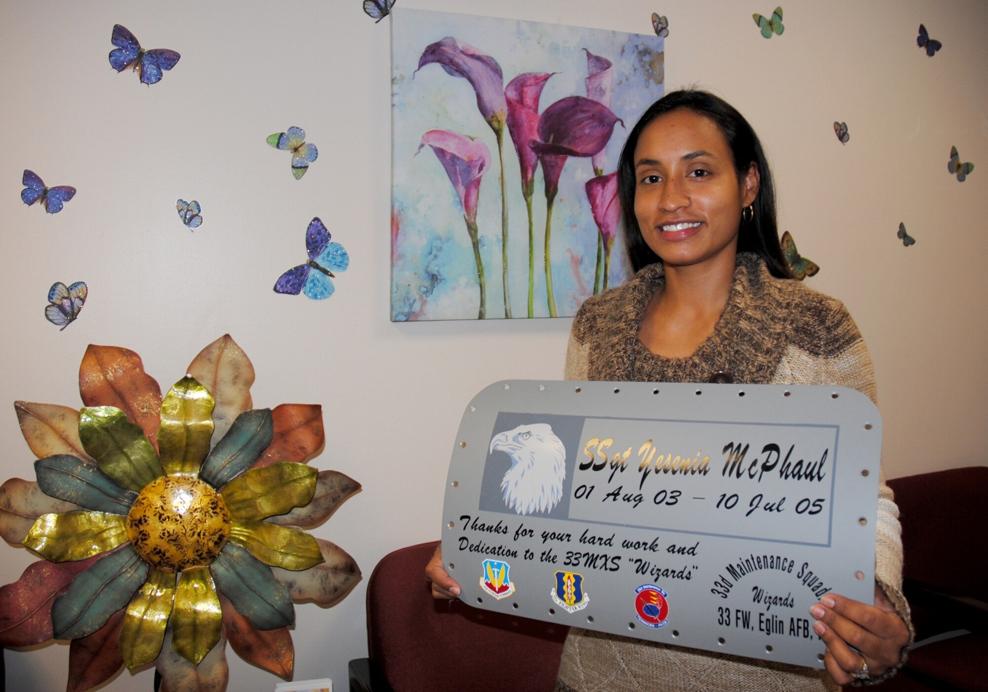 Yesenia McPhaul, 319th Medical Operation Squadron medical support assistant, poses with a commemorative aircraft panel in the Medical Treatment Facility on Grand Forks Air Force Base, N.D., Nov. 7, 2014. The panel was given to McPhaul as a keepsake for her time as an active-duty service member. Prior to her current position, McPaul served in the Air Force aircraft maintenance career field. (U.S. Air Force photo/Staff Sgt. Luis Loza Gutierrez)