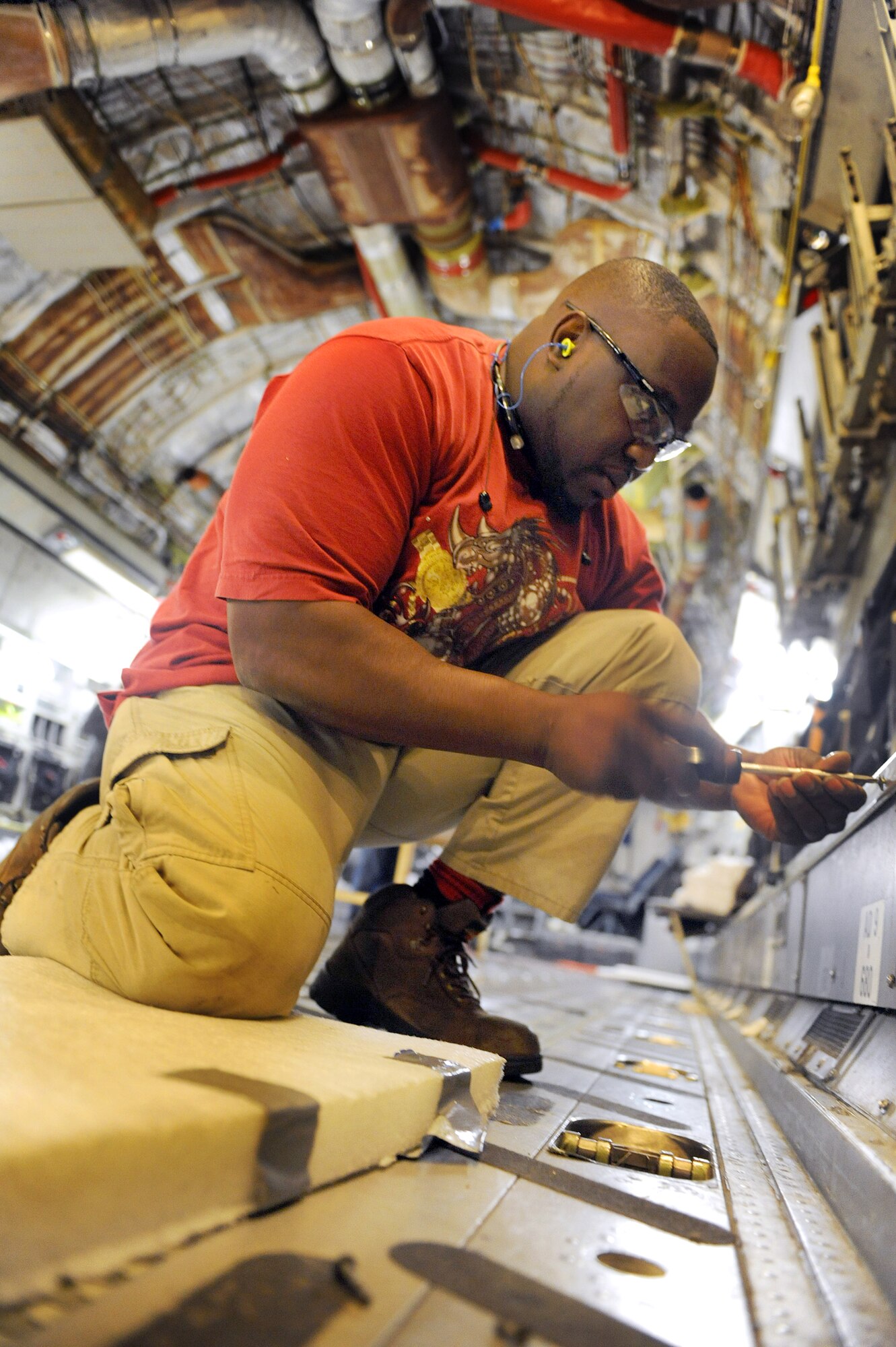 Derrick Chatmon, 562nd Aircraft Maintenance Squadron aircraft mechanic, installs kick panels on the C-17 being modified with an on board fire suppression system. The system operates much like a controlled fire extinguisher, dispersing inert gas which prevents an aircraft from being engulfed in flames when it's hit during enemy engagement. (U.S. Air Force photo by Tommie Horton)