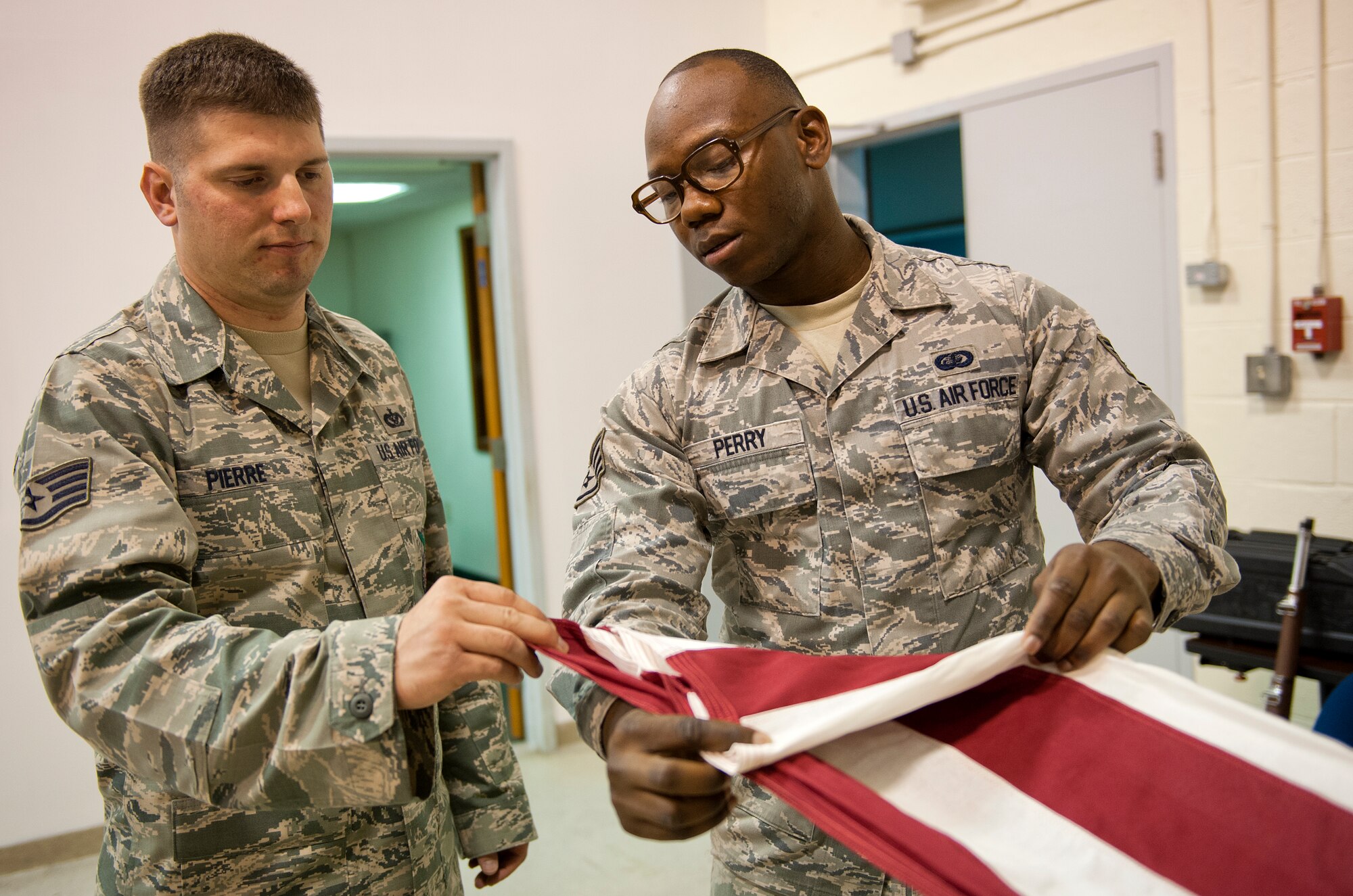 Staff Sgt. Monteco Perry, 65th Air Base Wing Honor Guard non-commissioned officer in charge, shows Staff Sgt. Douglas Pierre, a firefighter with the 65th Civil Engineer Squadron, flag folding techniques at Lajes Field, Azores, Portugal, Nov. 13, 2014. A ceremonial guardsman is an individual of good reputation, having integrity, ethical conduct and exhibiting standards which merit respect; responsible for protecting and overseeing the maintenance of standards on and off duty. (U.S. Air Force photo/Staff Sgt. Zachary Wolf/Released)