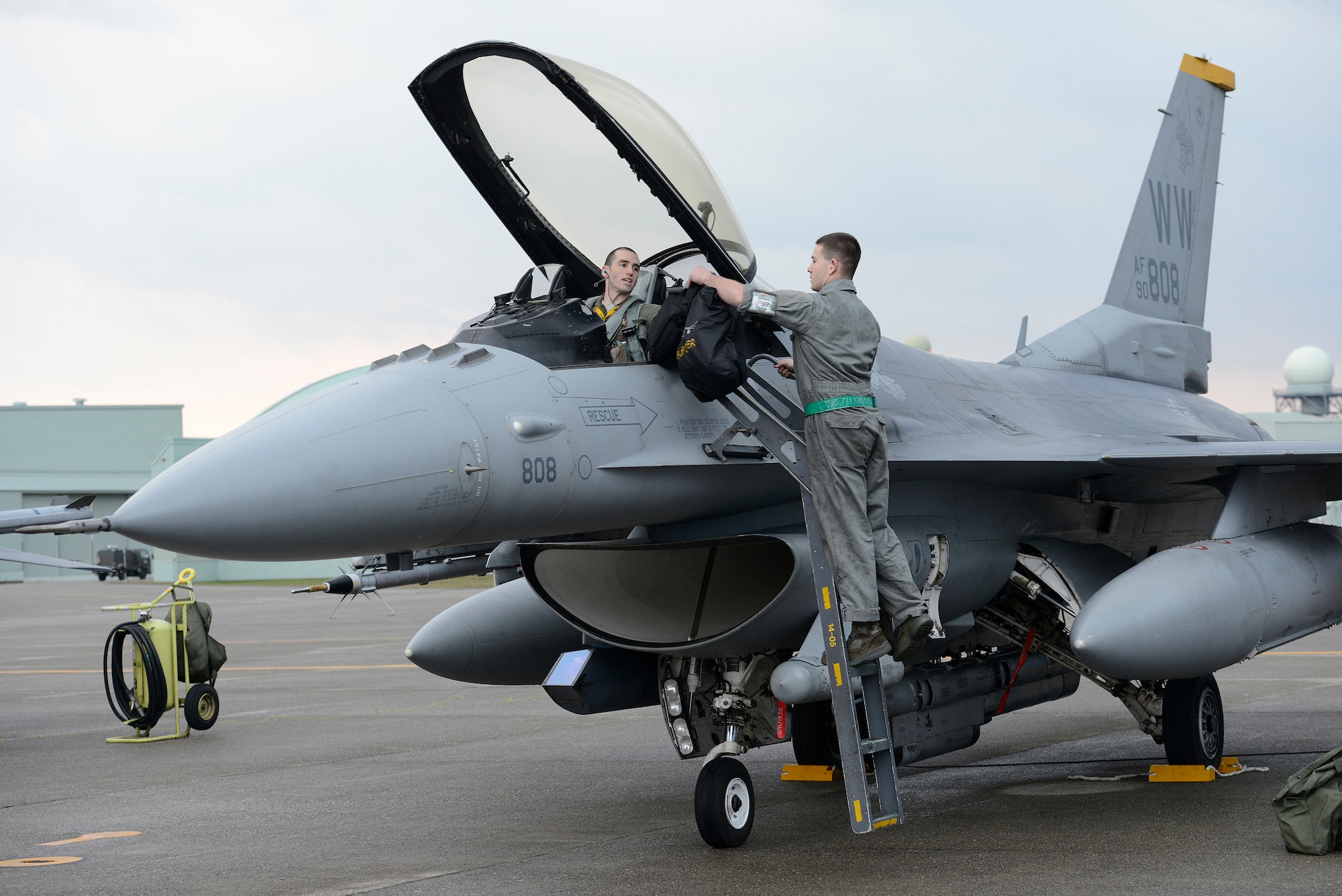 U.S. Air Force 1st Lt. Andrew Buttitta, 14th Fighter Squadron pilot, hands his flight gear to Airman 1st Class Matthew McLaughlin, 14th Aircraft Maintenance Unit crew chief, after flying an F-16 Fighting Falcon during an Aviation Training Relocation mission at Komatsu Air Base, Japan, Nov. 12, 2014. The ATR program directs U.S. Air Force units to conduct training away from their duty station to provide a noise respite for those living in the community surrounding their home station. ATRs provide an indispensable field training environment for enhancing mutual understanding of each country’s tactics, communication protocols, procedures, and general interoperability. Buttitta is one of 120 Airmen from Misawa Air Base, Japan, supporting ATR missions at Komatsu. (U.S. Air Force photo by Staff Sgt. Alyssa C. Wallace/Released)