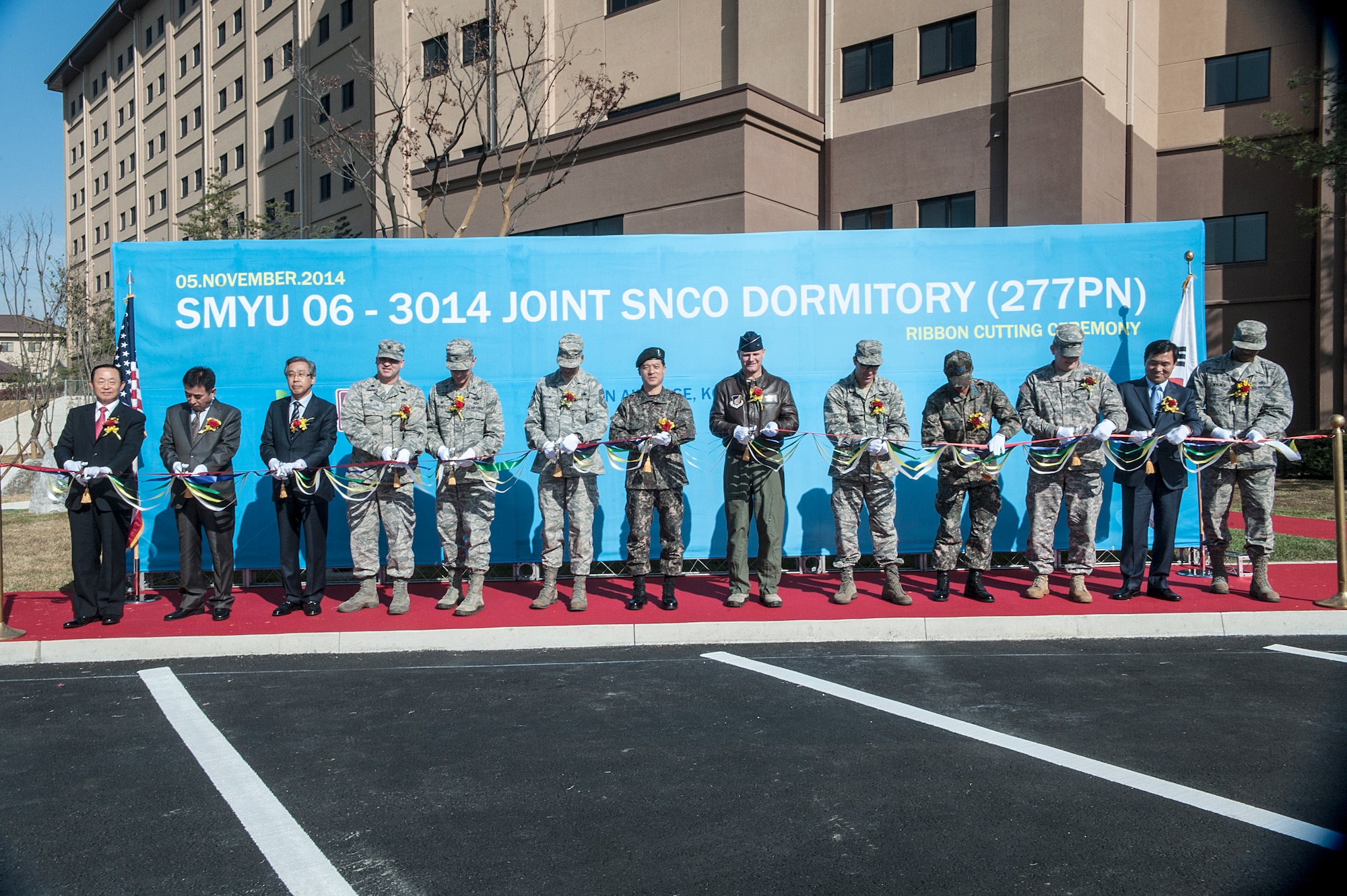 Osan Air Base leadership and Hyundai Engineering and Construction Company managing directors cut a ribbon during the Senior NCO dorm ribbon cutting ceremony at Osan AB, Republic of Korea, Nov. 5, 2014. The new dorm will house 277 residents with a single occupancy apartment style room. Each room will have one bedroom, one bathroom, living room, kitchen and washer and drier unit. The dormitory will feature an exercise room, lounge room, business center, and multipurpose room. (U.S. Air Force photo by Senior Airman Matthew Lancaster)