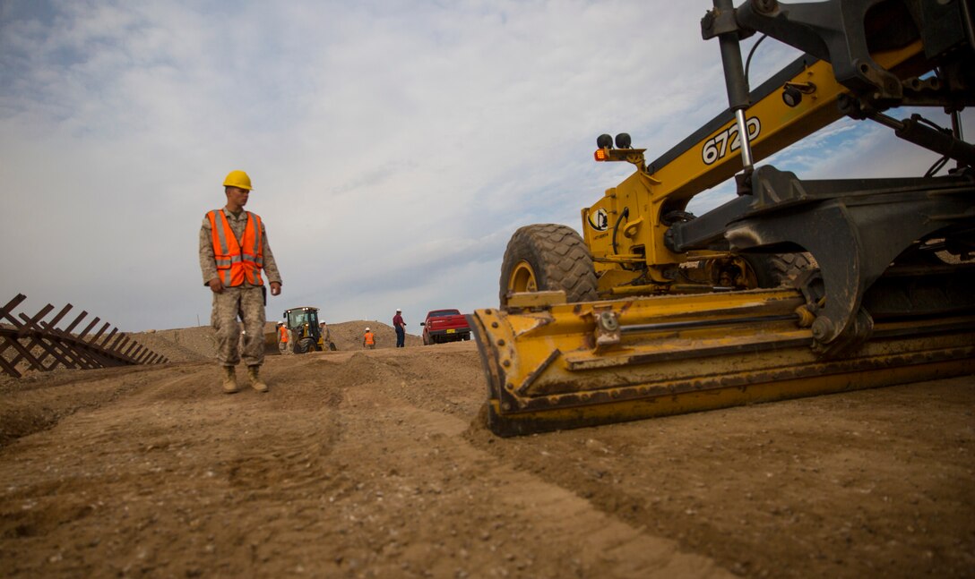 Cpl. Austin Smith, a heavy equipment operator with Marine Wing Support Squadron 371, guides the tractor as it levels the ground at the construction site in El Centro, Calif., Feb. 25. The joint units of MWSS-371, based in Marine Corps Air Station Yuma, Ariz., and 7th Engineer Support Battalion, based in Marine Corps Base Camp Pendleton, Calif., worked together to enhance the homeland security of the nation.    