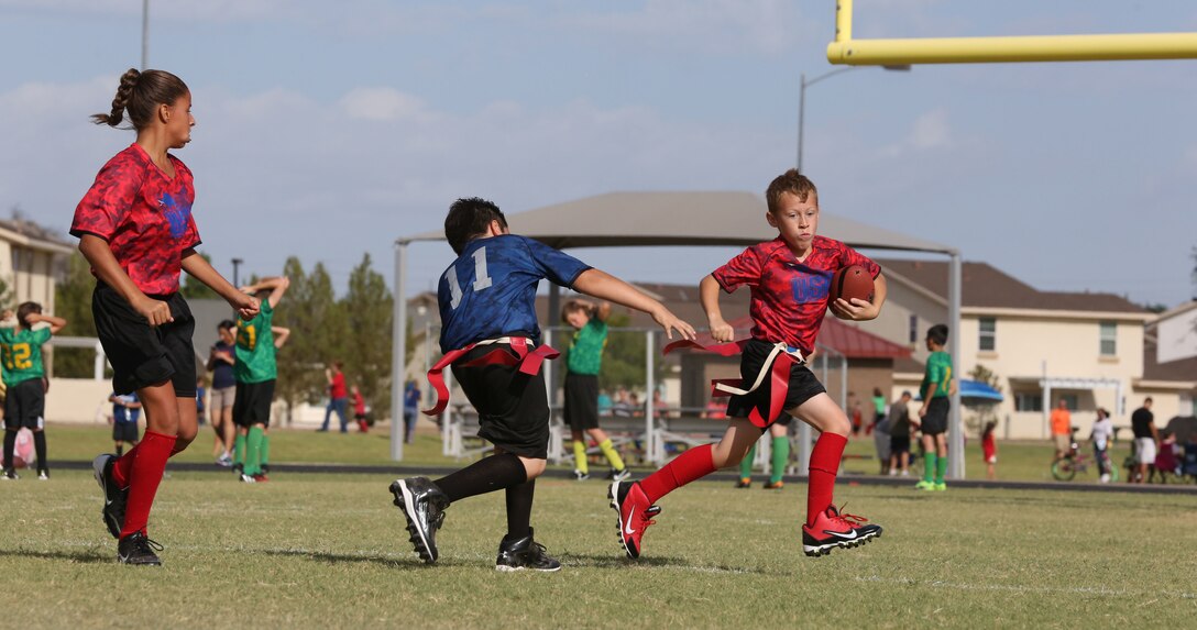 Team USA’s runner narrowly avoids being “tackled” by a player from The Cowboys during a flag football game hosted by Marine Corps Community Services Youth Sports Program Saturday, Sept. 27, 2014 on Marine Corps Air Station Yuma, Ariz.  Flag football substitutes traditional tackling with pulling off the opposing runner’s flags, providing a safe alternative for younger kids who enjoy playing the sport.