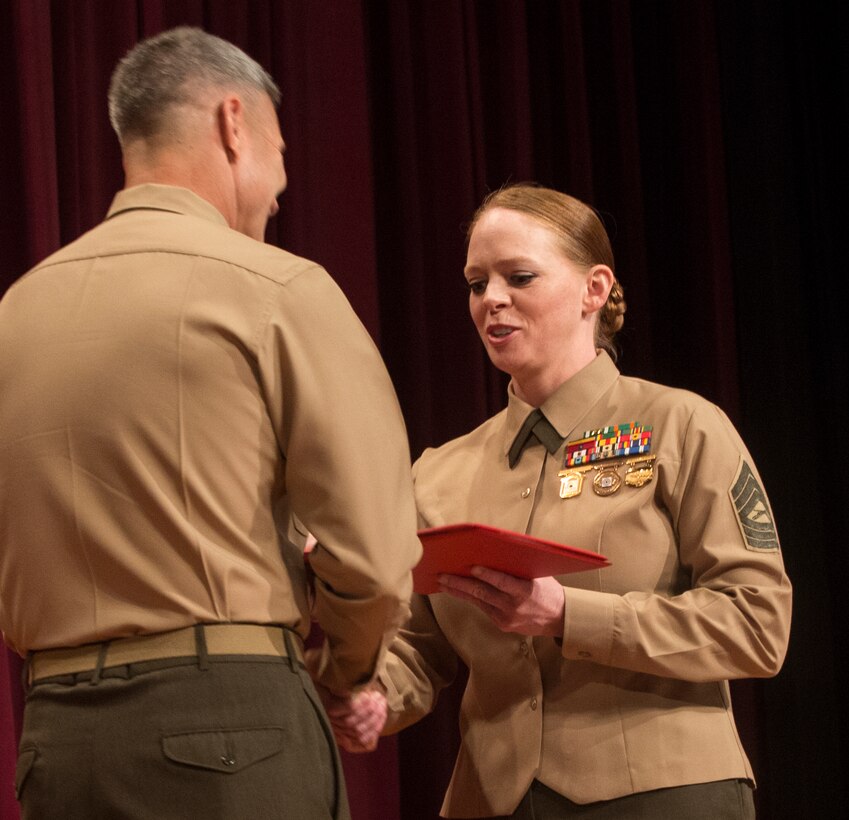 Master Sergeant Julia Watson, an instructor for the Marksmanship Training Unit at Marine Forces Reserve New Orleans, accepts her silver medal in the Competition-In-Arms Western Divisional individual pistol competition at the base theatre of Marine Corps Base Camp Pendleton, Calif., March 7, 2014. With the silver medal, Watson secured the final eight points she needed to become a distinguished pistol shooter. 