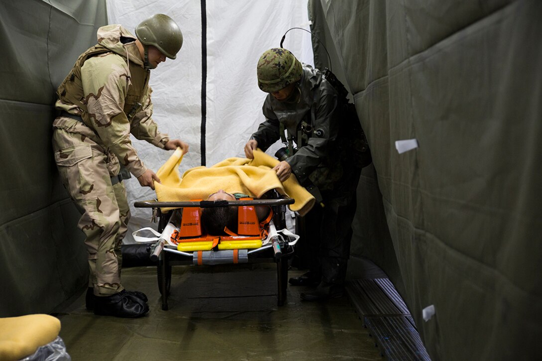 A Marine with Marine Aircraft Group 12 and a member of the Japan Ground Self-Defense Force’s 102nd Central Nuclear Biological Chemical Weapon Defense Unit take care of a victim during Chemical Biological Radiological Nuclear and Hazardous Material Emergency Response Operations aboard MCAS Iwakuni, Japan, Nov. 8, 2014. This was the first time the MCAS Iwakuni Fire Station, Marine Aircraft Group 12 and the Japan Ground Self-Defense Force’s 102nd Central Nuclear Biological Chemical Weapon Defense Unit collaborated to conduct this type of training.