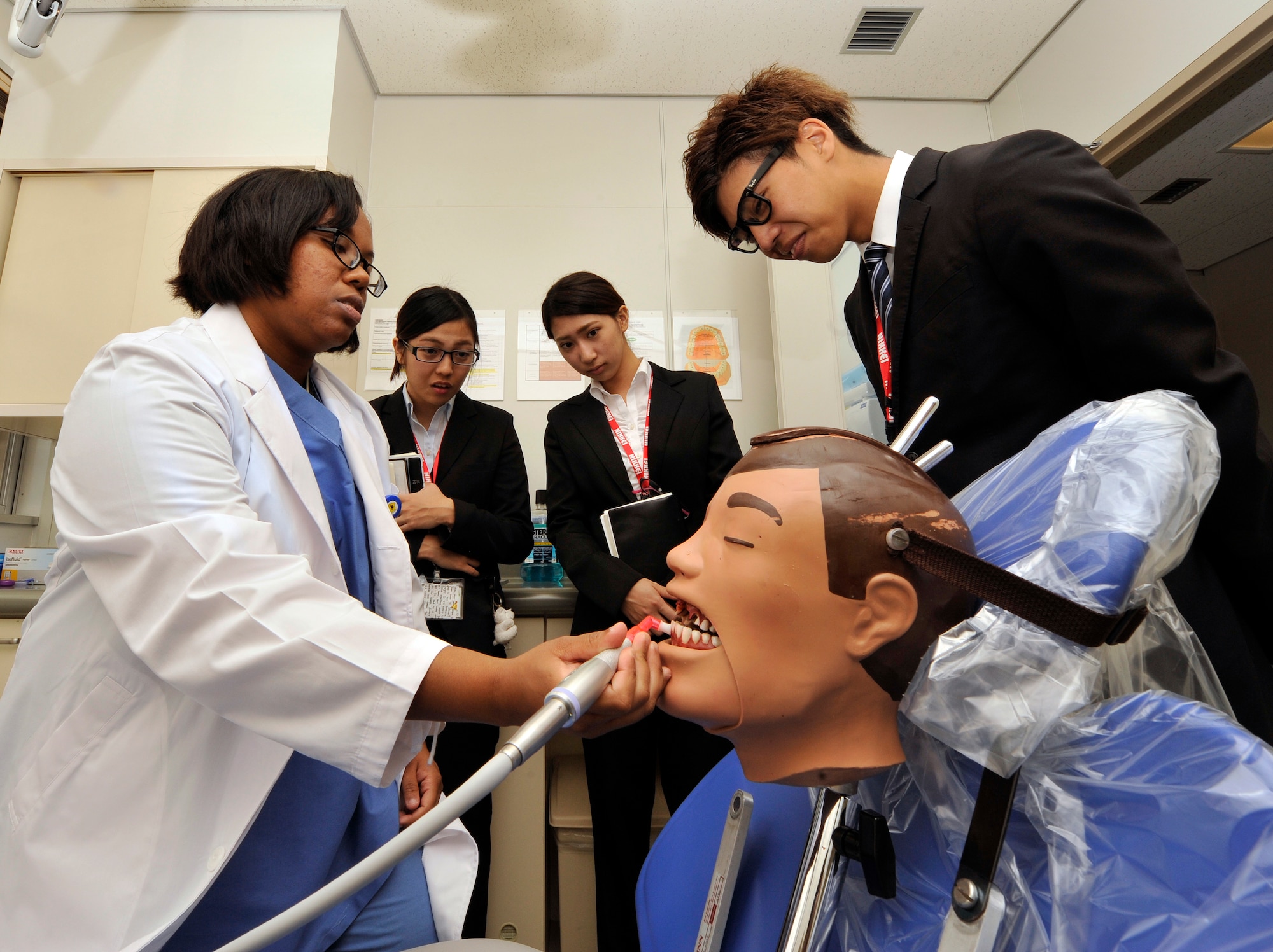 U.S. Air Force Staff Sgt. Consuelo Cabrera, 18th Dental Squadron preventive dentistry technician, demonstrates cleaning teeth on a mannequin for students from the Nikkei College of Business in Okinawa City during a base facility tour on Kadena Air Base, Japan, Nov. 14, 2014. The program supports the local community by hosting students to help improve their English skills. It also offers an opportunity for Air Force members to interact with the students and show what the Air Force does during facility tours. (U.S. Air Force photo/Naoto Anazawa)
