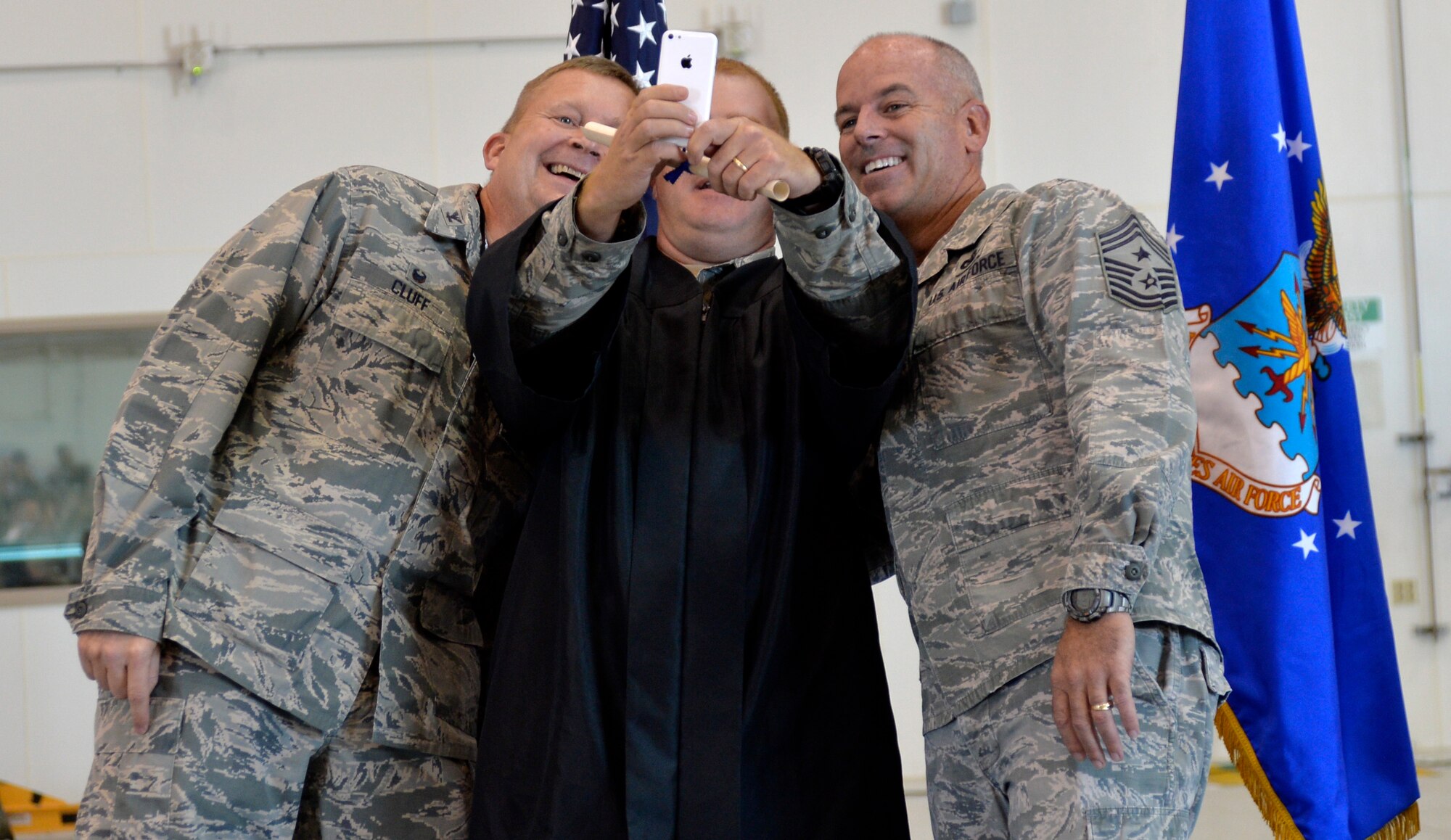 Master Sergeant Bryan Teeples, 15th Reconnaissance Squadron first sergeant, takes a selfie with Col. James Cluff, 432nd Wing/432nd Air Expeditionary Wing commander, and Chief Master Sergeant Butch Brien, 432nd WG/432nd AEW command chief, at Creech Air Force Base’s first-ever Community College of the Air Force graduation, which took place on base Nov. 14, 2014. Combined, Nellis and Creech Air Force Bases have more than 400 Airmen who received diplomas during the fall CCAF graduating class. (U.S. Air Force photo by Staff Sgt. Adawn Kelsey)