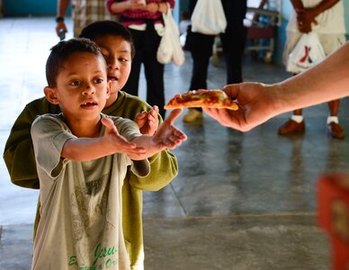 A young boy receives a slice of pizza from U.S. Air Force Capt. Samuel McClellan, Joint Task Force-Bravo command chaplain, during the Friendship Chapel’s sponsored visit to the Sisters of Charity Orphanage in Comayagua, Honduras, Nov. 16, 2014.  The Sisters of Charity Orphanage is one of seven different orphanages from around the Comayagua Valley that the U.S. military personnel assigned to JTF-Bravo have supported over the past 17 years. In addition to spending time with interacting with children, members have also collected and donated much-needed supplies and food, as well as helped in minor construction work on the buildings in which the children live. (U.S. Air Force photo/Tech. Sgt. Heather Redman)