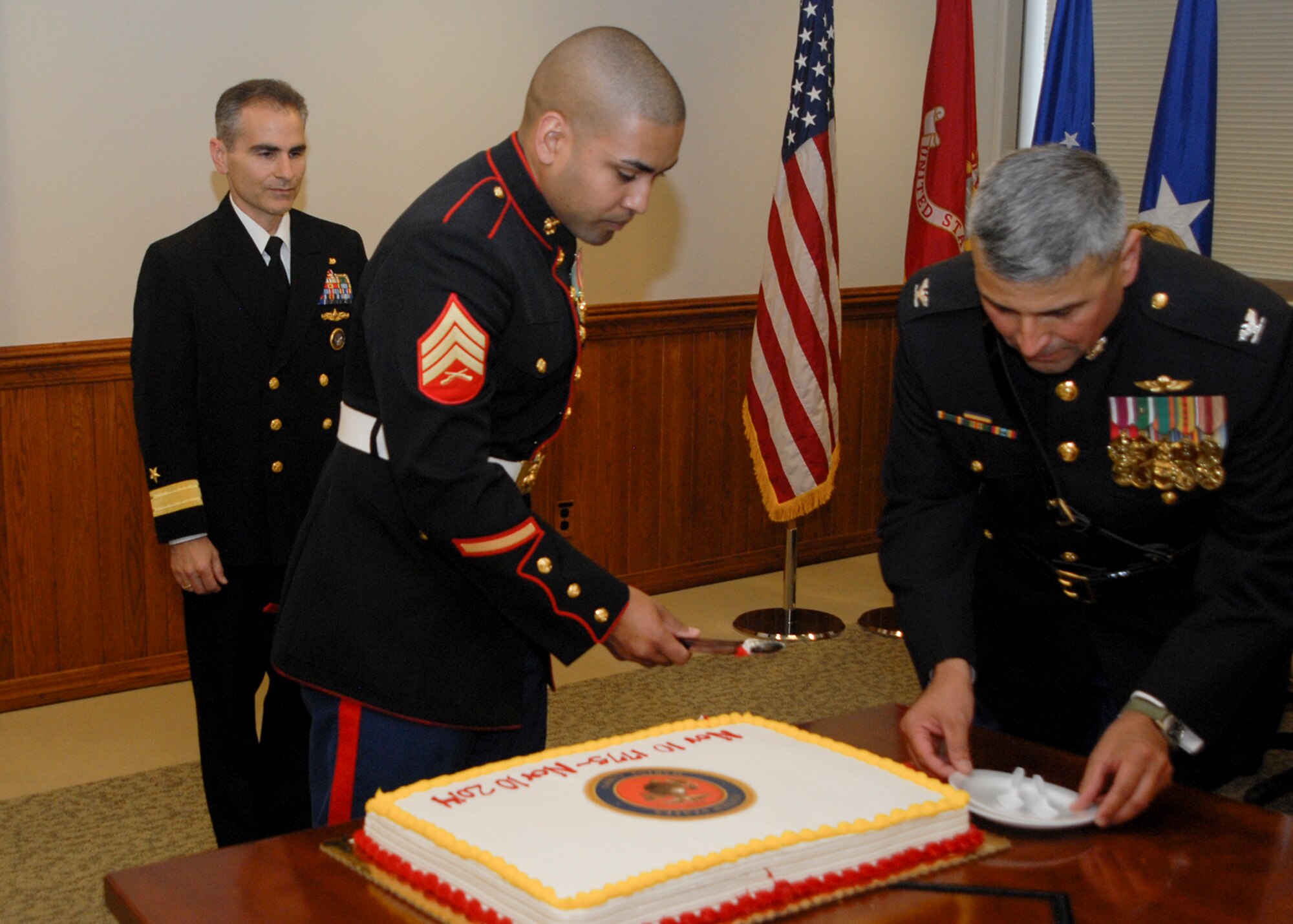 U.S. Navy Rear Adm. Brian Brown, deputy commander, Joint Functional Component Command for Space, participates in a cake-cutting ceremony with U.S. Marine Corps Col. Edward Quinonez, a reservist assigned to the Operations, Fires and Effects Coordination cell, 1st Marine Expeditionary Force, Camp Pendleton, Calif., and Marine Corps Sgt. Moses Figueroa, office administrator, JFCC Space, during a Marine Corps Birthday celebration here, Nov. 12, 2014. It is tradition that the most senior and most junior Marine present cut the first piece of cake using a ceremonial saber. (U.S. Air Force photo by Capt. Nicholas Mercurio/Released)