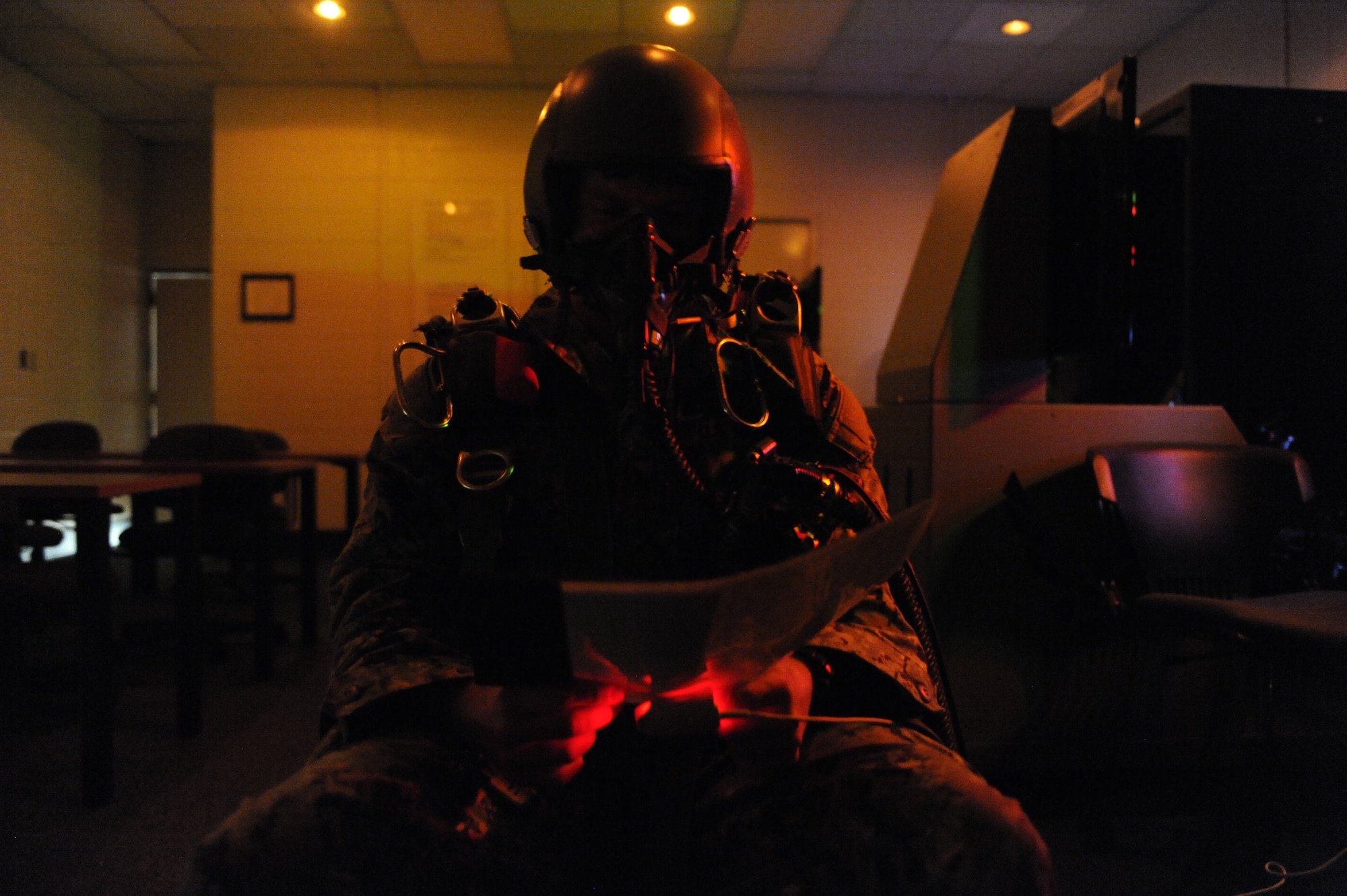 U.S. Navy Petty Officer 2nd Class Sean Purvis looks at a color chart during a night flying test on a reduced oxygen breathing device at Langley Air Force Base, Va., Nov. 14, 2014. During the night test, the mixture of gases changed to show the aviators the effects pressure changes can have on vision. (U.S. Air Force photo by Staff Sgt. Natasha Stannard/Released)