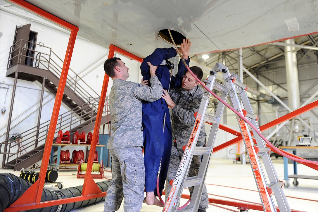 U.S. Air Force Senior Airmen Mathew Wambles (left) along with his colleague Kyle Quiggle, rescue a dummy from a small opening located under the wing/fuel cell as part of an annual Fuel Systems Extraction Exercise on Nov. 10 at Offutt Air Force Base, Neb.  Fuel systems repairmen and firefighters must be knowledgeable on the retrieval of crew that may have lost consciousness while performing repairs in the fuel cell.  (U.S. Air Force photo by Josh Plueger/Released)