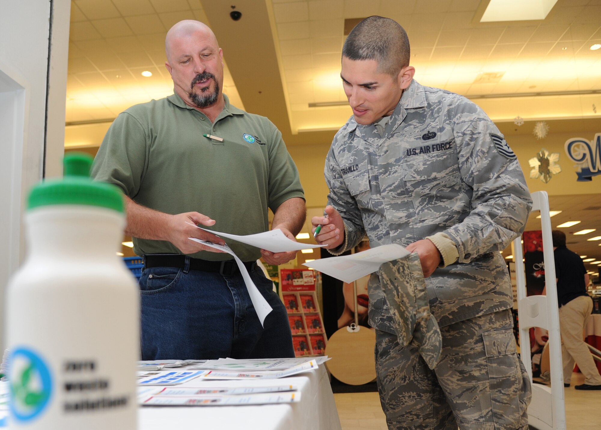 Duane Olsen, Zero Waste Solutions recycling technician, provides educational recycling material to Tech. Sgt. Alberto Trujillo, 81st Force Support Squadron Airman Leadership School instructor, at an American Recycling Day booth Nov. 14, 2014, in the base exchange, Keesler Air Force Base, Miss.  The base environmental office and the recycling center worked together to provide pertinent information to shoppers. (U.S. Air Force photo by Kemberly Groue)
