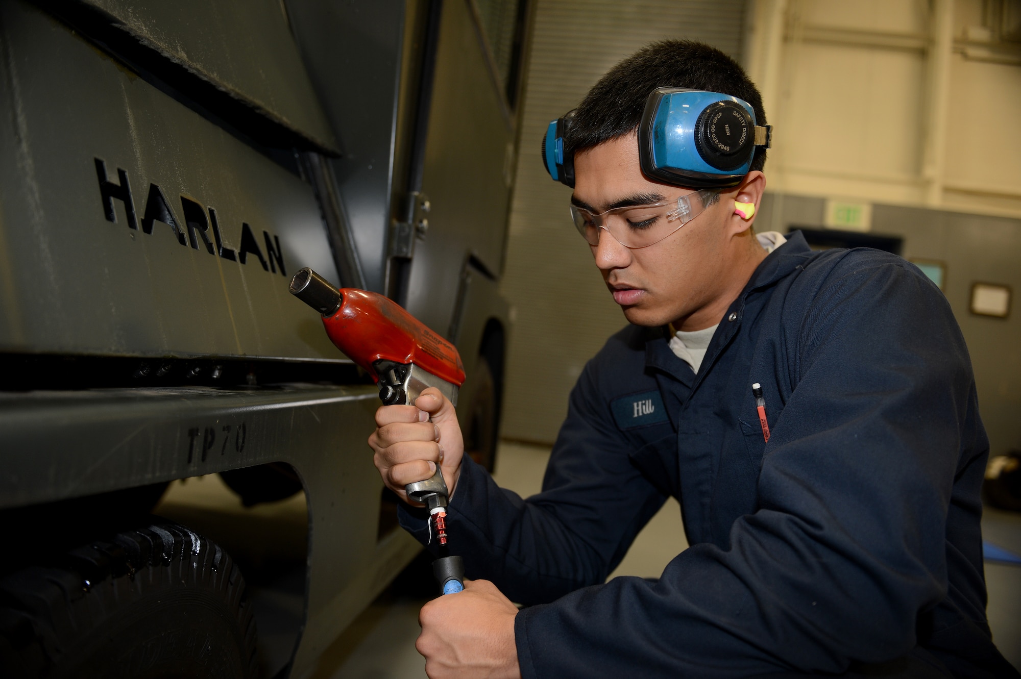Airman 1st Class Tyler Hill, 627th Logistics Readiness Squadron fire truck maintainer, attaches a pneumatic impact wrench to an air hose Nov. 5, 2014, at Joint Base Lewis-McChord, Wash. Hill is required to wear double hearing protection to use the pneumatic impact wrench as indicated by the red air coupler at the bottom of the tool. (U.S. Air Force photo/Airman 1st Class Keoni Chavarria)