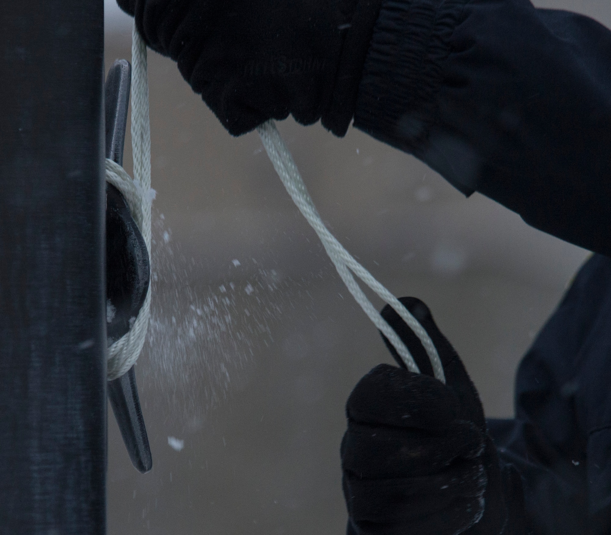 Officer Robert Hendrick, Department of the Air Force police officer, unties the halyard rope to lower the flag at Mountain Home Air Force Base, Idaho, Nov. 13, 2014. As one person lowers the flag another person prepares to catch it and make sure it’s held securely. (U.S. Air Force photo by Airman 1st Class Jessica H. Smith/RELEASED)