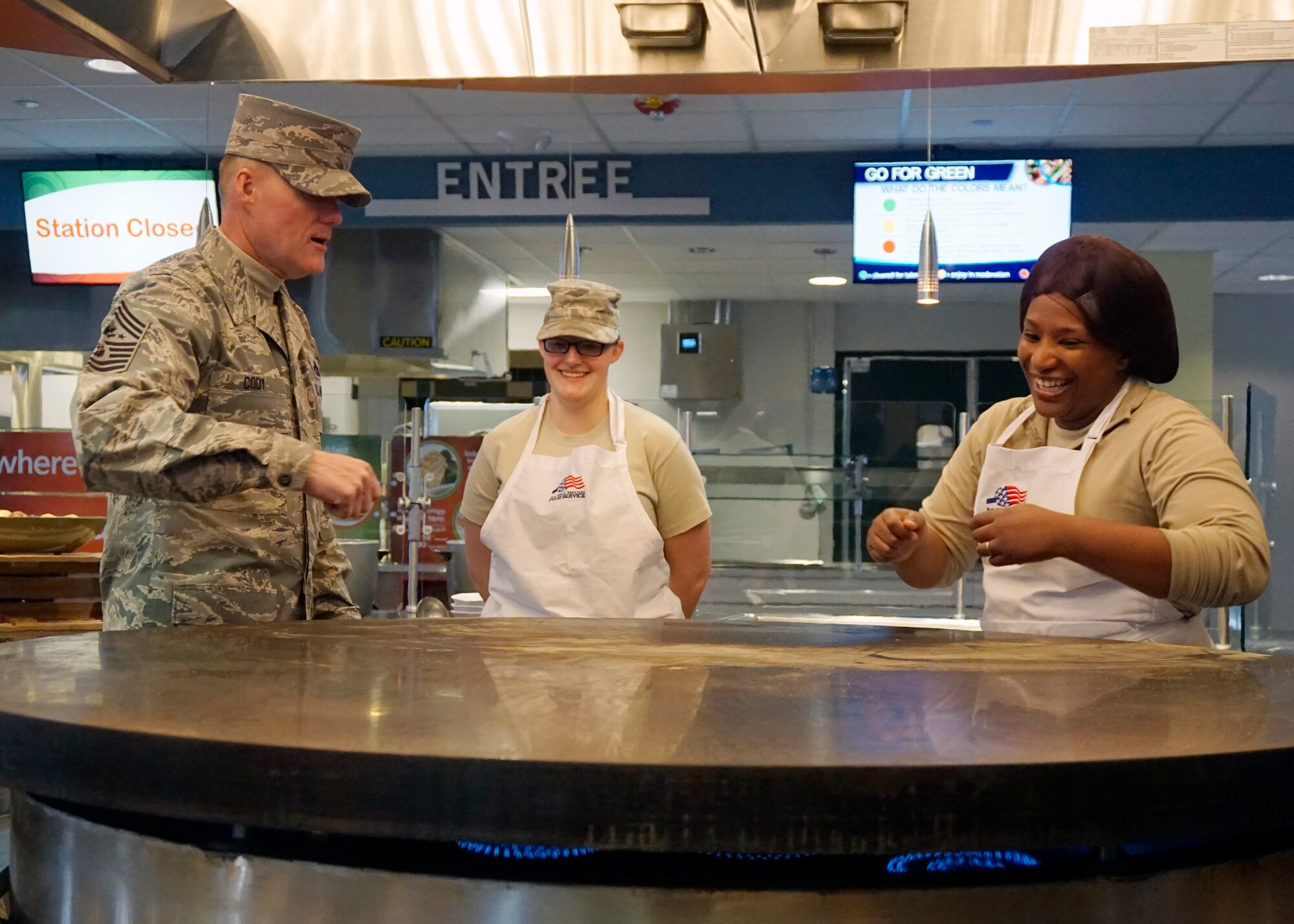 Staff Sgt. Michelle Morris and Senior Airman Brittany Junk, 90th Force Support Squadron, show  Chief Master Sgt. of the Air Force James Cody the various methods available for chefs to cook on the Chadwell Dining Facility go-global station Nov. 15, 2014 at F.E. Warren Air Force Base, Wyo. The station is the primary location to cook multi-national entrees for Airmen to enjoy. (U.S. Air Force photo by Lan Kim)