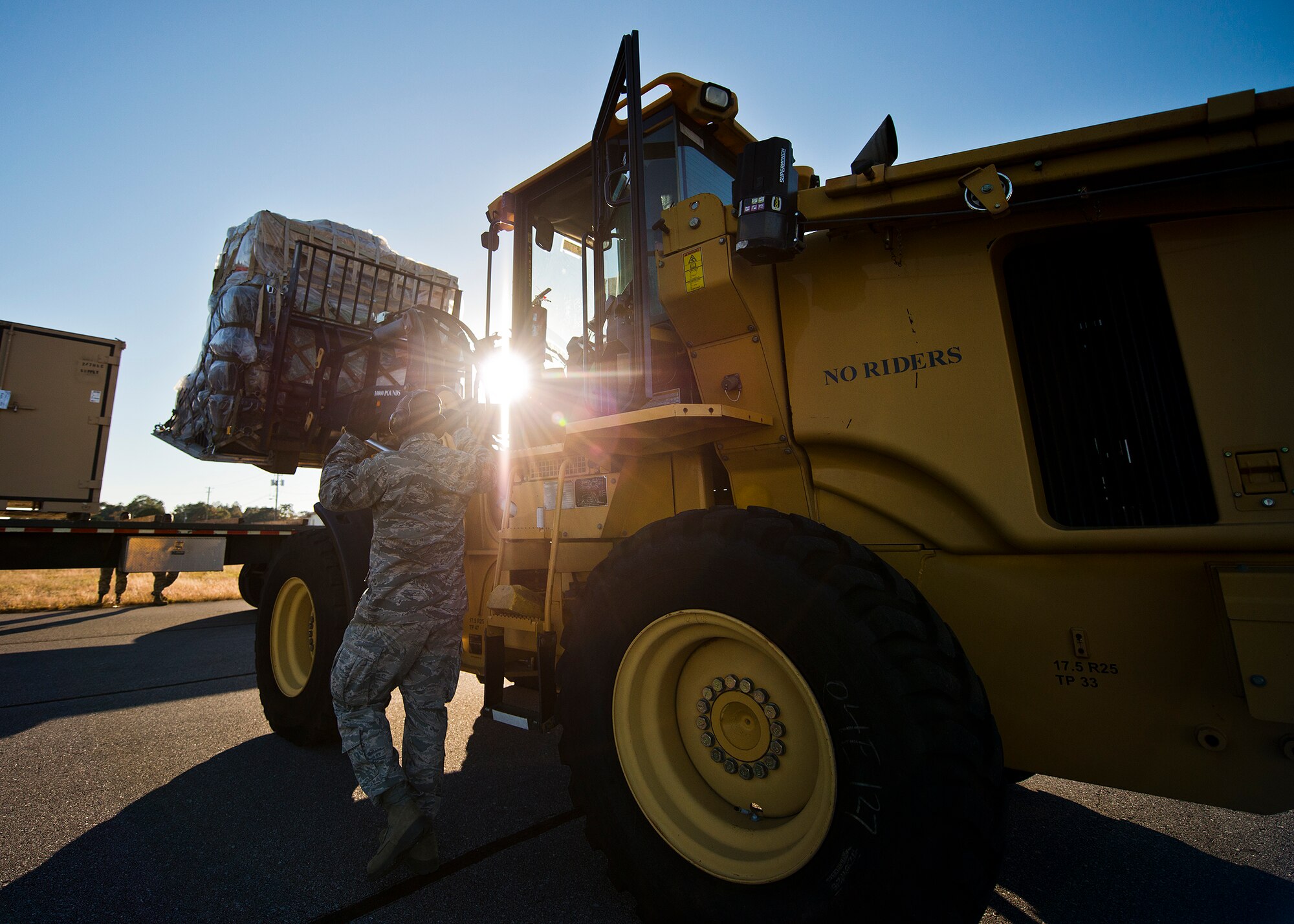 A 96th Logistics Readiness Squadron’s air terminal operations Port Dawg directs a front end loader carrying cargo toward a flatbed truck at Eglin Air Force Base, Fla., Nov. 14.  The Port Dawgs unloaded approximately eight Army pallets from the C-5 Galaxy that day. The section moves an average of 160 tons of cargo and 570+ passengers per month.  (U.S. Air Force photo/Samuel King Jr.)