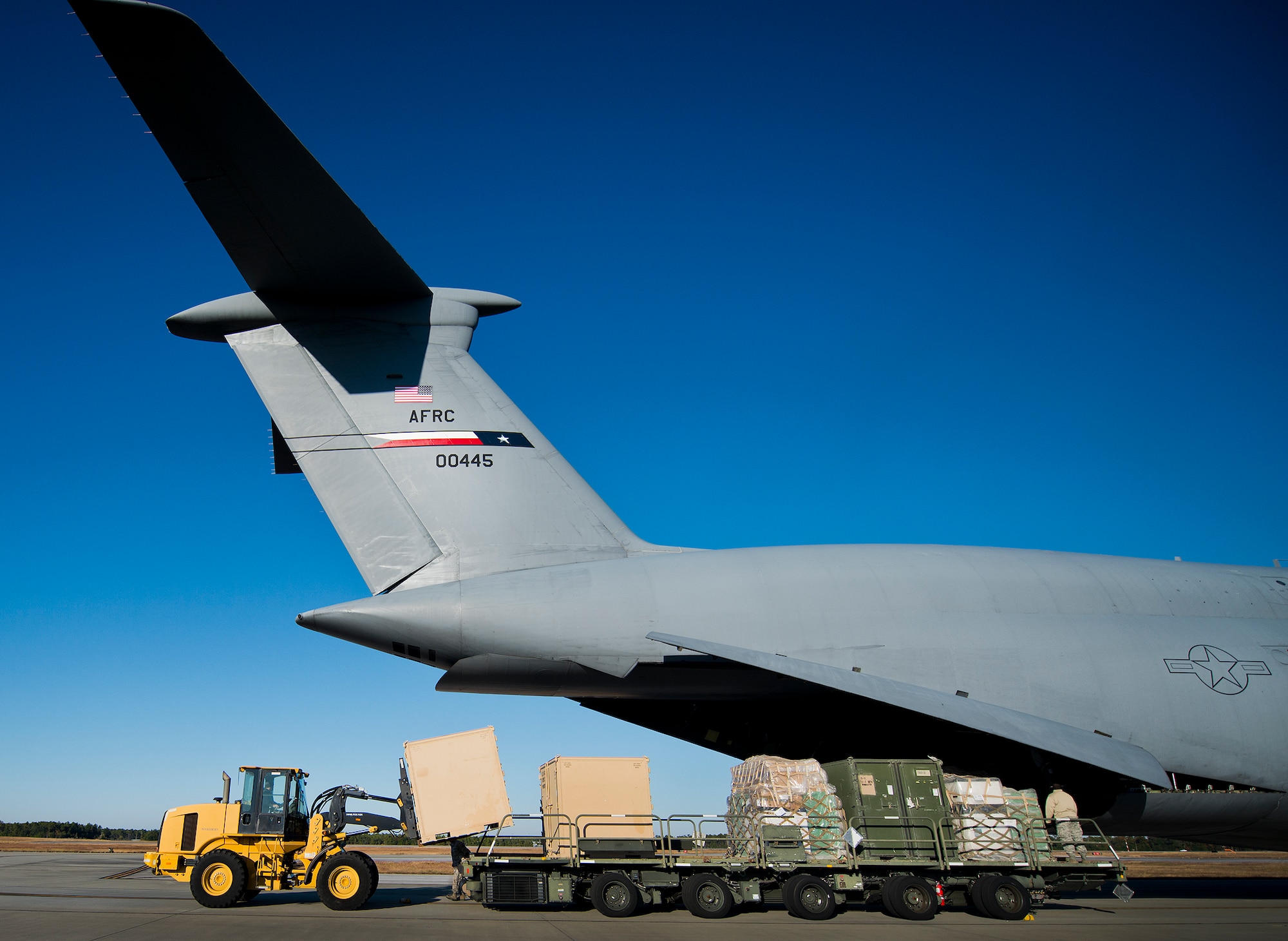 A 96th Test Wing front end loader picks up a metal cargo box after being offloaded from the 433rd Airlift Wing’s C-5 Galaxy at Eglin Air Force Base, Fla., Nov. 14.  The 96th Logistics Readiness Squadron’s air terminal operations Port Dawgs unloaded approximately eight Army pallets from the C-5. The section moves an average of 160 tons of cargo and 570+ passengers per month.  (U.S. Air Force photo/Samuel King Jr.)
