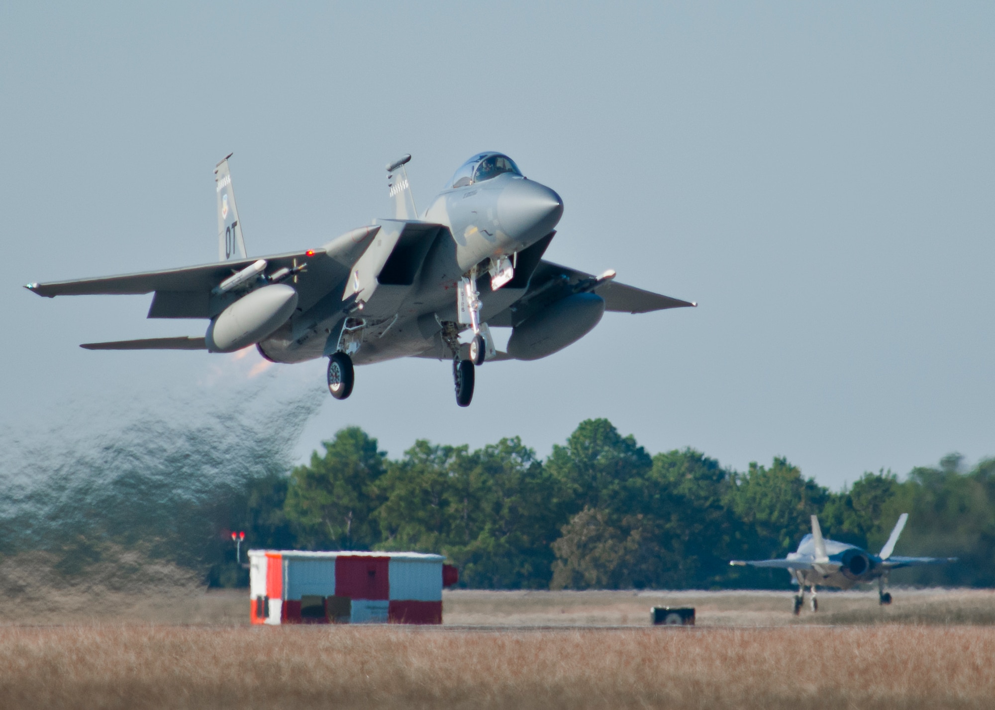 A 53rd Wing F-15 Eagle takes off from one of Eglin Air Force Base’s runways as a 33rd Fighter Wing F-35 Lightning II taxies onto another.  The F-15 is used for operational test missions while the F-35 is used to train pilots. (U.S. Air Force photo/Samuel King Jr.)