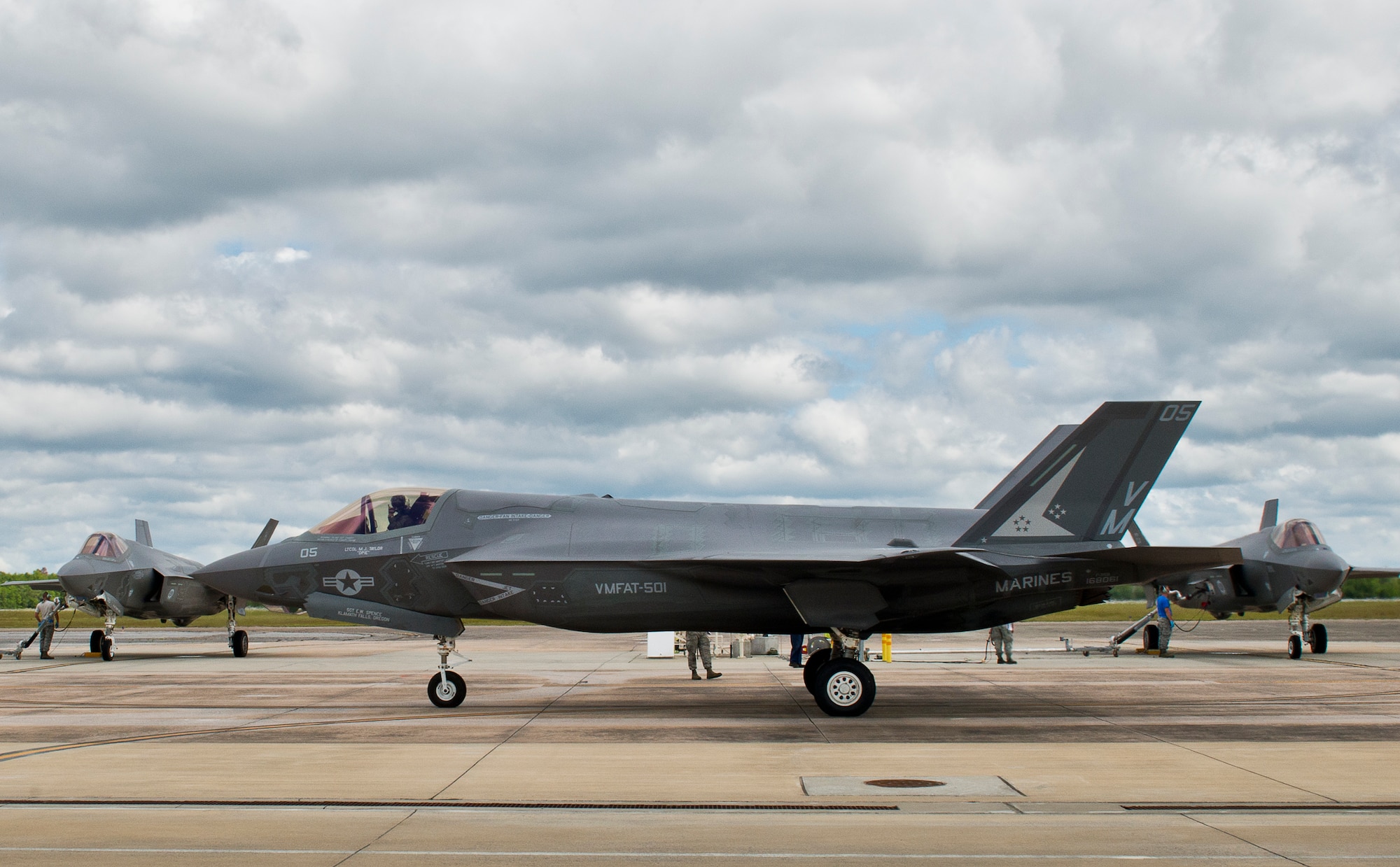 A Marine F-35B Lightning II from the Marine Fighter Attack Training Squadron 501 rolls by the 33rd Fighter Wing hot pit refueling area as two F-35As receive fuel at Eglin Air Force Base, Fla.  All of the F-35 variants use the refueling areas in conjunction with the 96th Logistics Readiness Squadron’s fuels flight. (U.S. Air Force photo/Samuel King Jr.)  