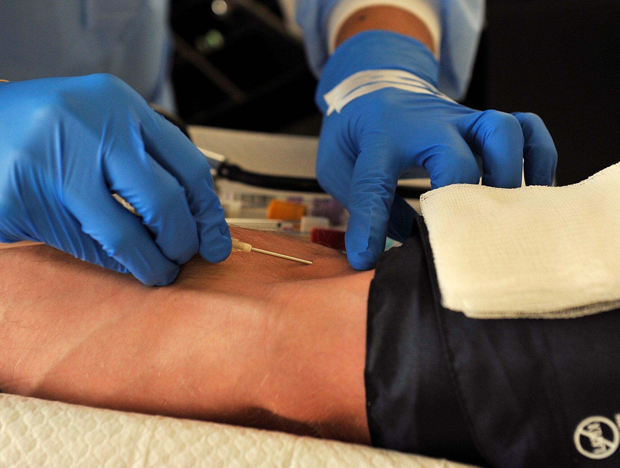 U.S. Navy Petty Officer 3rd Class Keith Williams, Armed Services Blood Bank Center hospital corpsman, inserts a needle into a patient's arm during a blood drive at the Exchange on Kadena Air Base, Japan, Nov. 13, 2014. The 18th Communications Squadron hosted the blood drive, and they plan to host one every four months to help support the Armed Services Blood Program. (U.S. Air Force photo by Naoto Anazawa/Released)